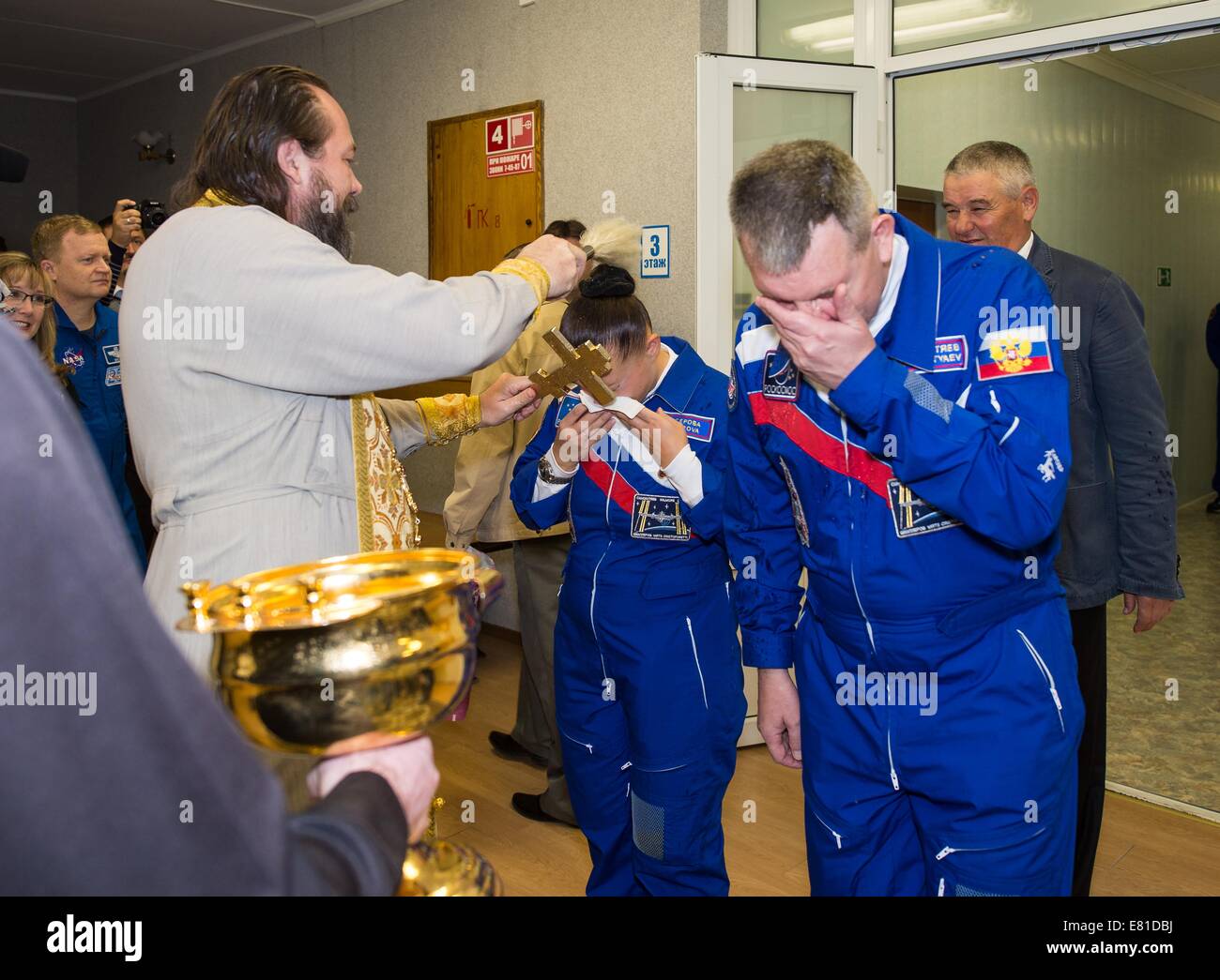 Stazione Spaziale Internazionale Expedition 41 cosmonauta Elena Serova di l'agenzia Spaziale Federale Russa riceve la tradizionale benedizione di un sacerdote russo ortodosso come comandante Alexander Samokutyaev asciuga il suo volto al cosmonauta Hotel prima del lancio del razzo Soyuz alla Stazione Spaziale Internazionale il 25 settembre 2014 di Baikonur in Kazakhstan. Samokutyaev, Serova e Wilmore permetterà di trascorrere i prossimi cinque mesi e mezzo vivere e lavorare a bordo della ISS. Foto Stock