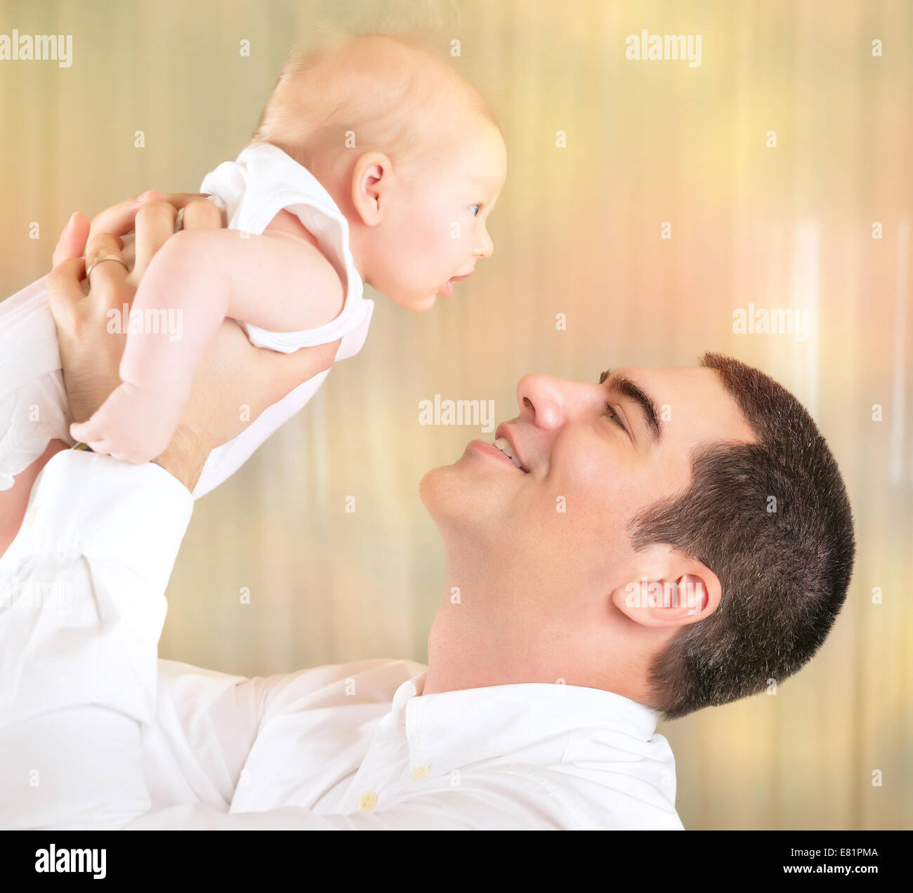 Padre Felice con la figlia del neonato sulla riproduzione a casa, allegro papà sollevamento piccolo bambino su mani, amore e felicità concept Foto Stock