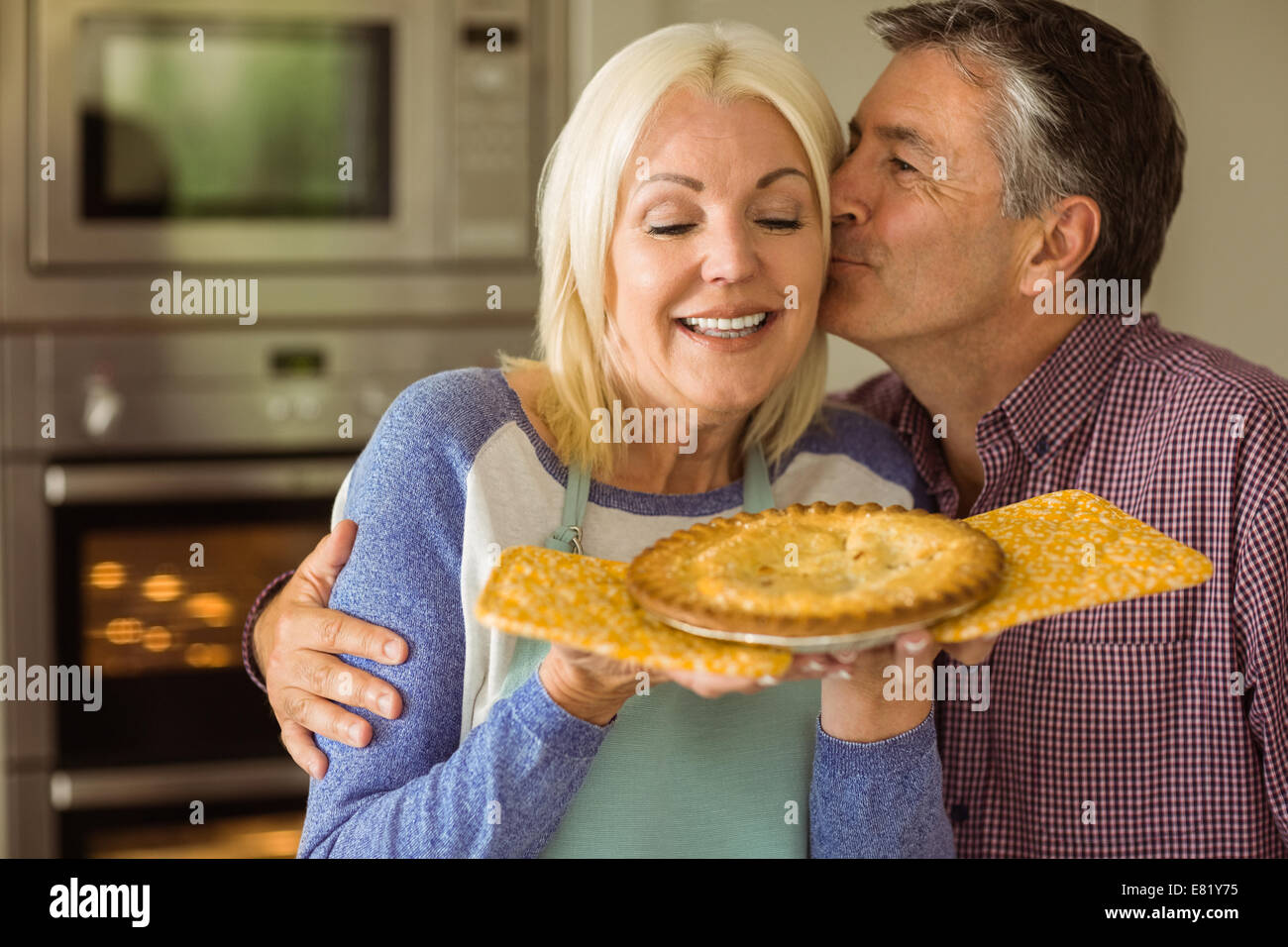 Bionda matura holding torta fresca con mio marito bacia Foto Stock