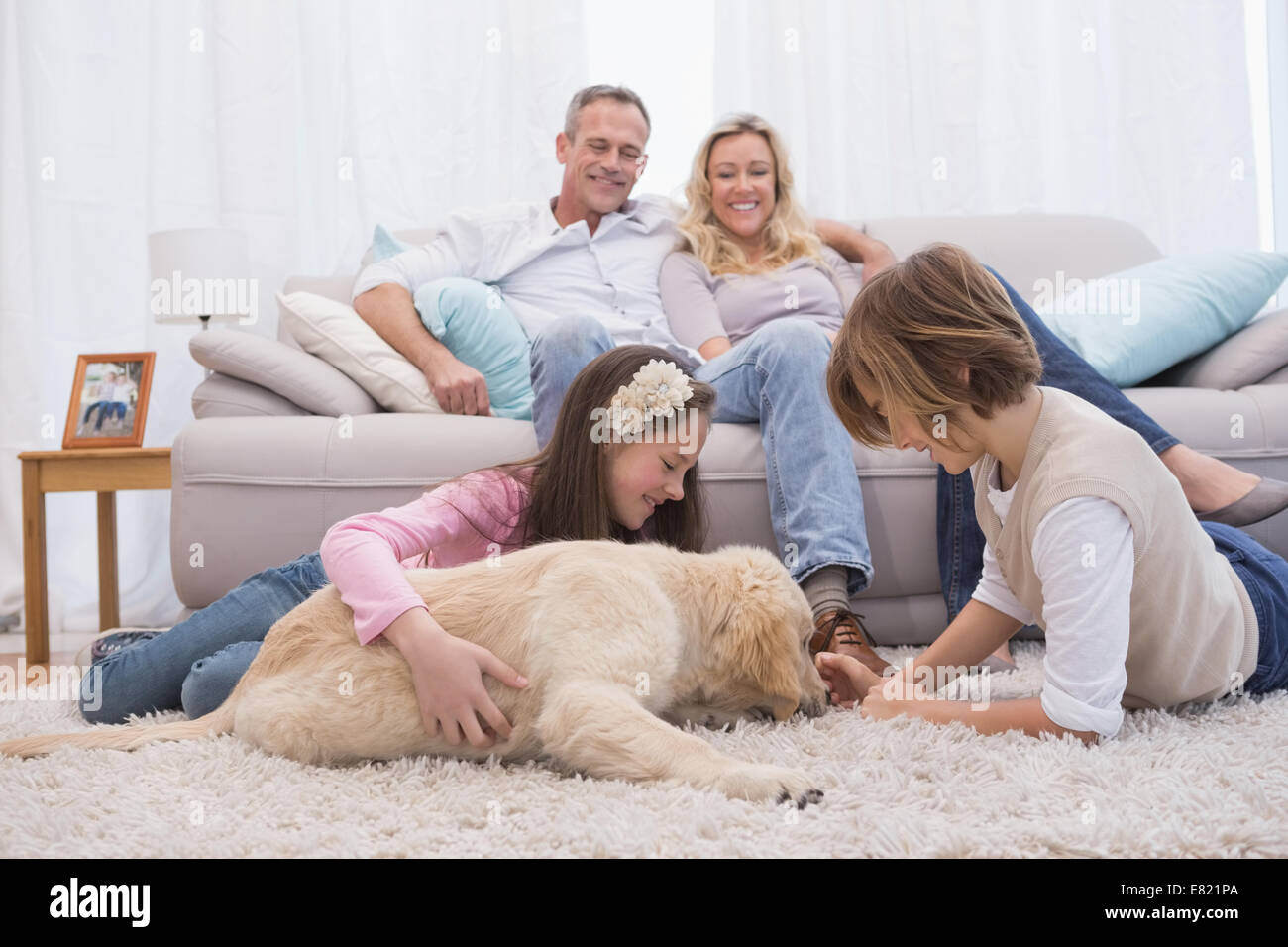 Simpatici fratelli giocando con il cane con i loro genitori sul divano Foto Stock