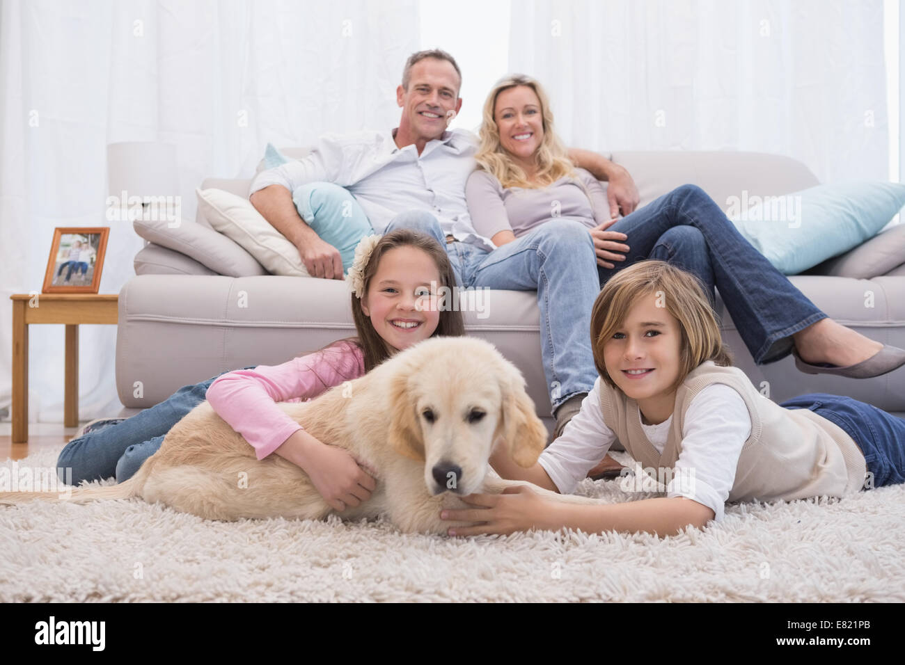 Simpatici fratelli giocando con il cane con i loro genitori sul divano Foto Stock