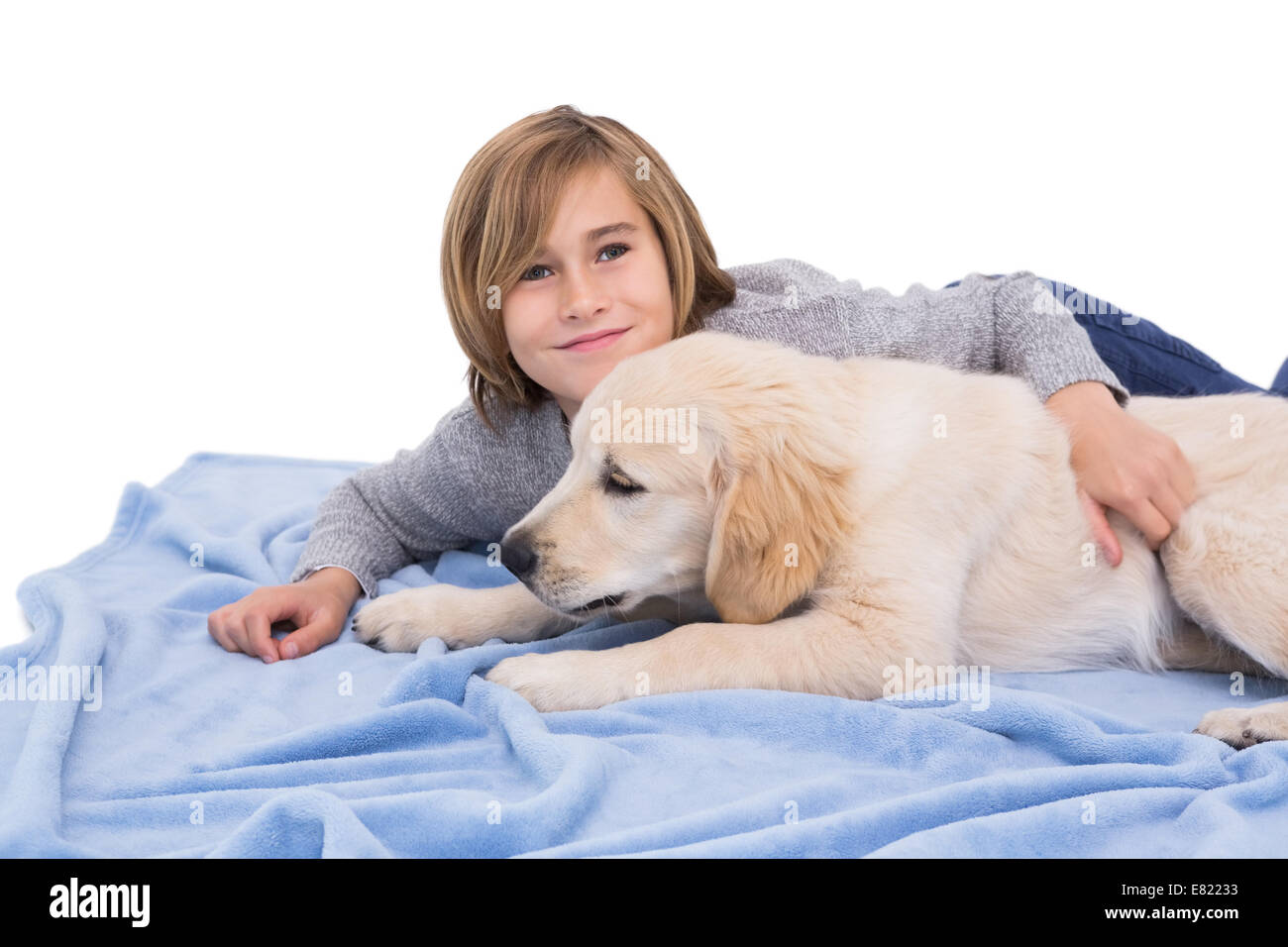Bambino strofinando il suo cane che giace su una coperta Foto Stock