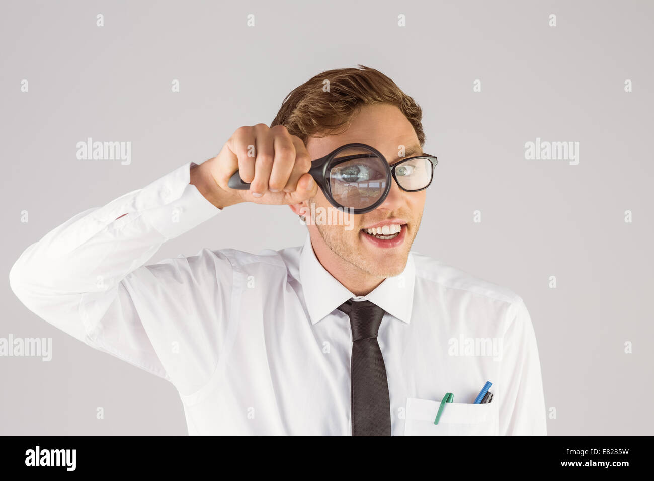 Geeky imprenditore guardando attraverso la lente di ingrandimento Foto Stock