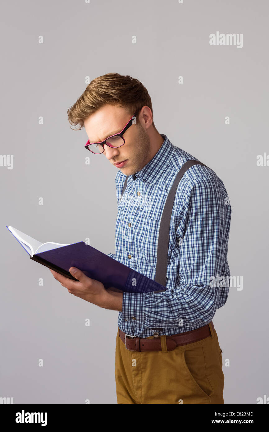 Geeky studente la lettura di un libro Foto Stock