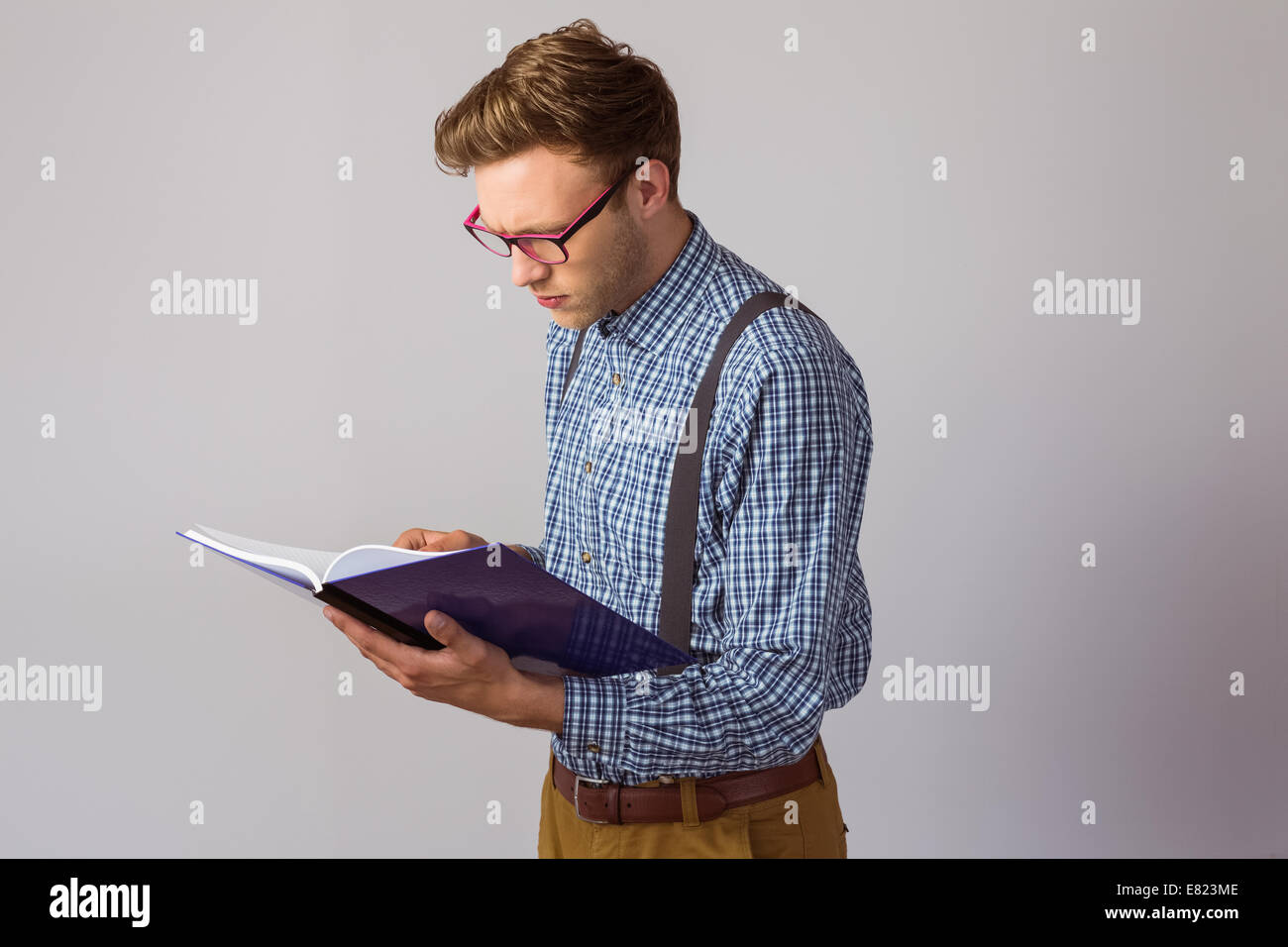 Geeky studente la lettura di un libro Foto Stock