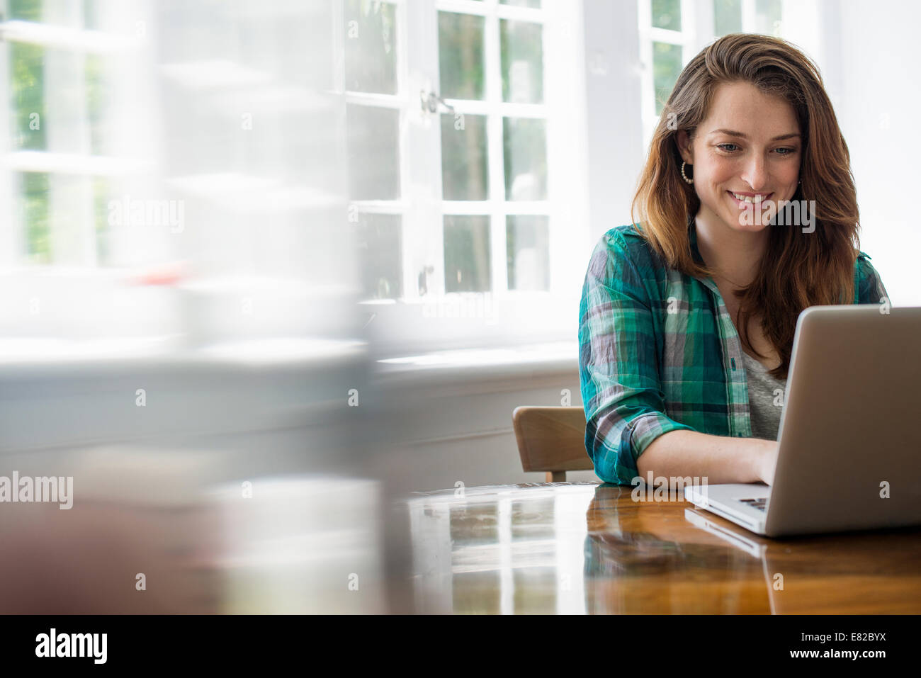 Donna sorridente con notebook in ufficio a casa. Foto Stock