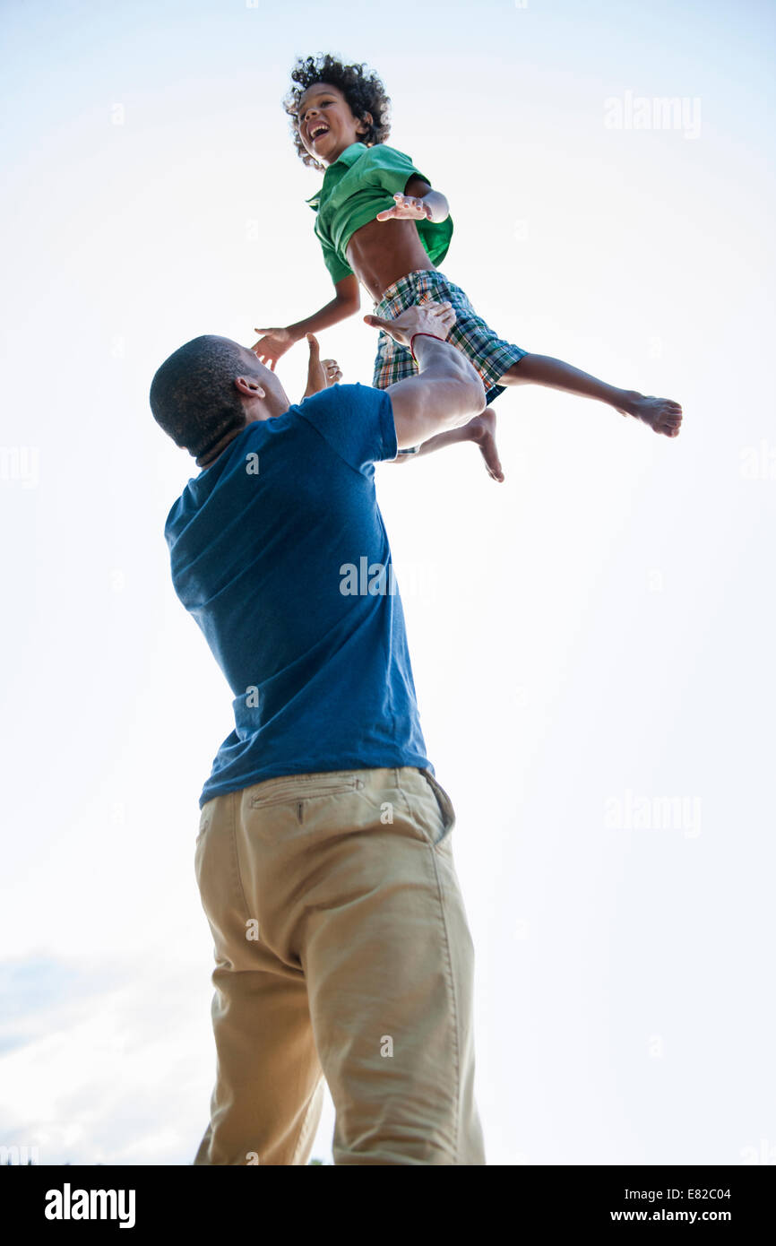 Un uomo di sollevare un piccolo ragazzo alto sopra la sua testa in gioco. Foto Stock