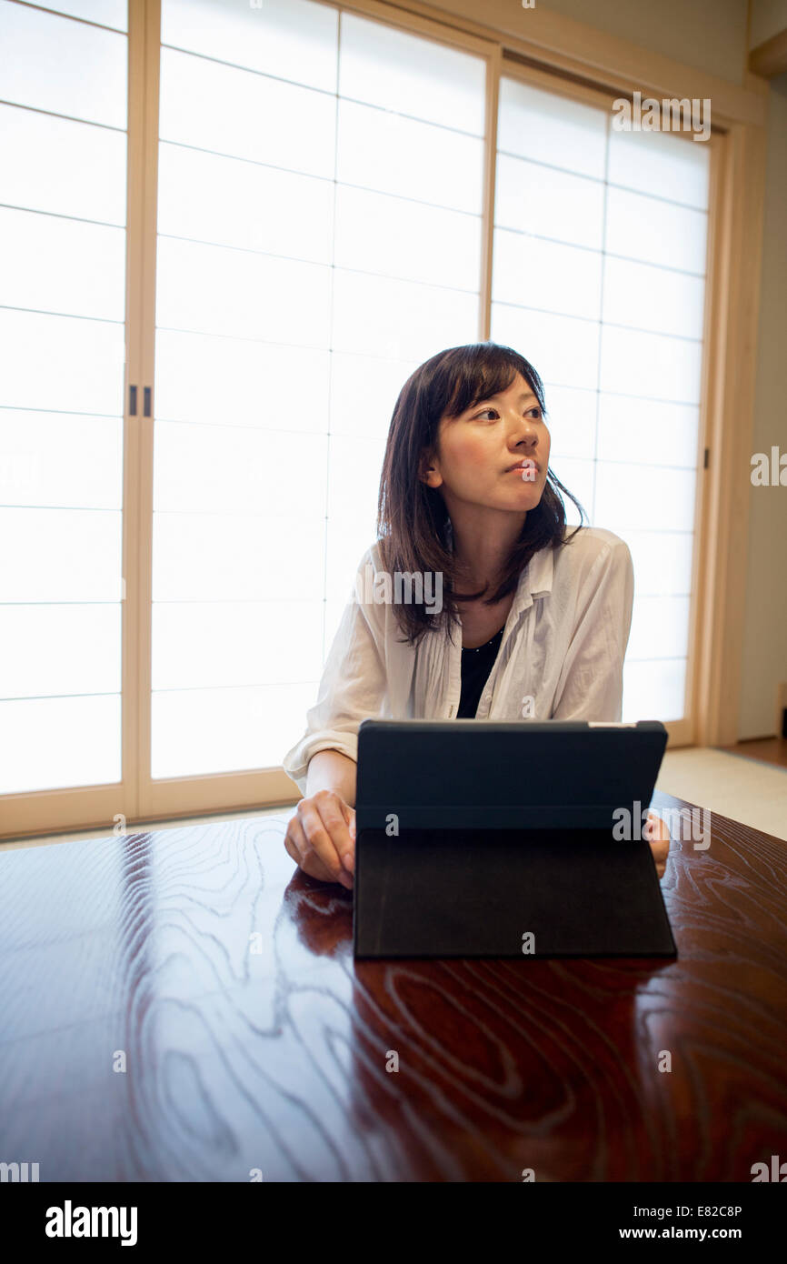 Una donna seduta a un tavolo con un computer portatile. Foto Stock