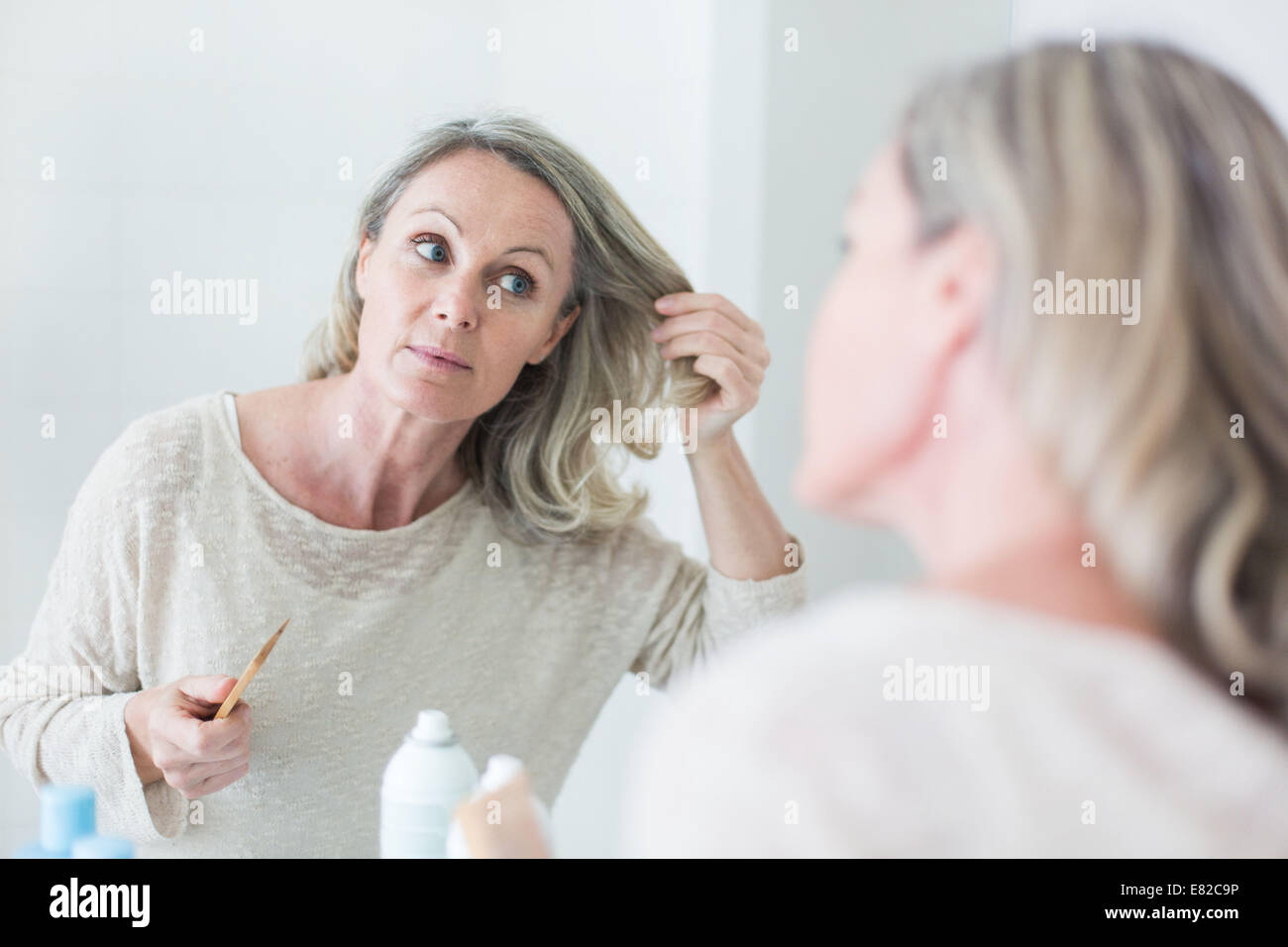 Donna di ispezionare i suoi capelli. Foto Stock