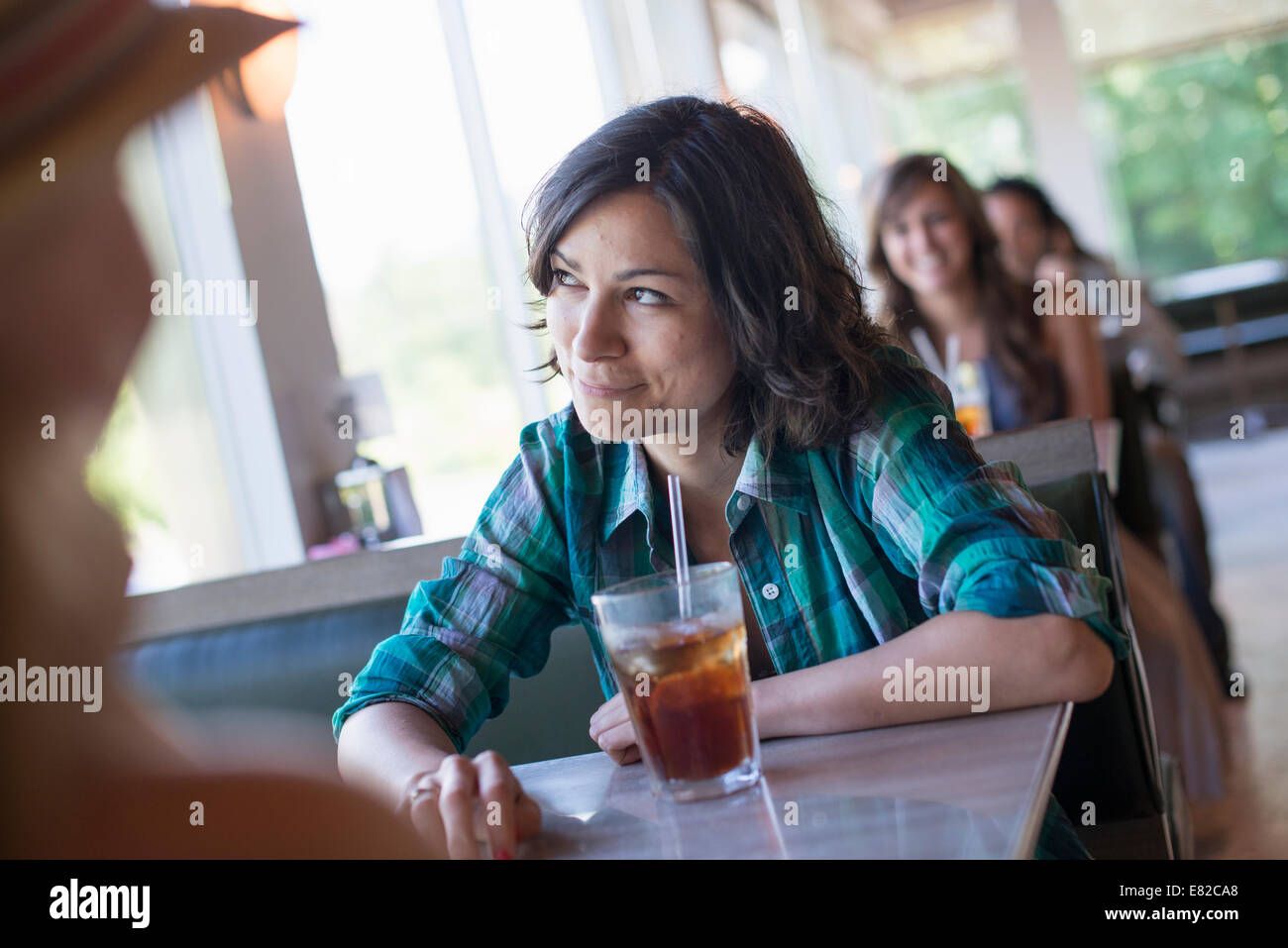 Una donna seduta a una cena guardando fuori della finestra. Un fresco drink con una cannuccia. Foto Stock