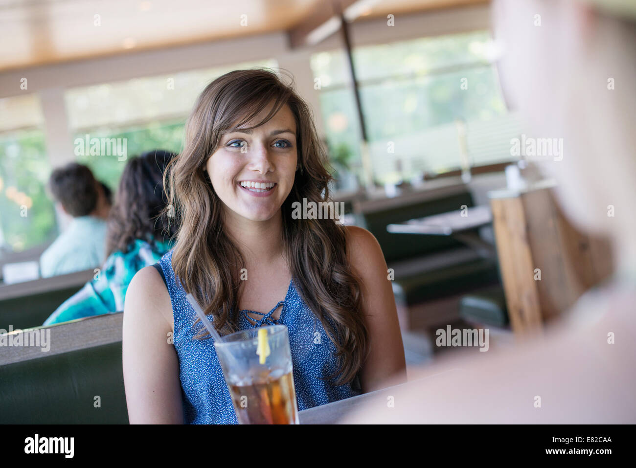 Una giovane donna seduta a un tavolo in un ristorante con una bevanda fresca. Foto Stock