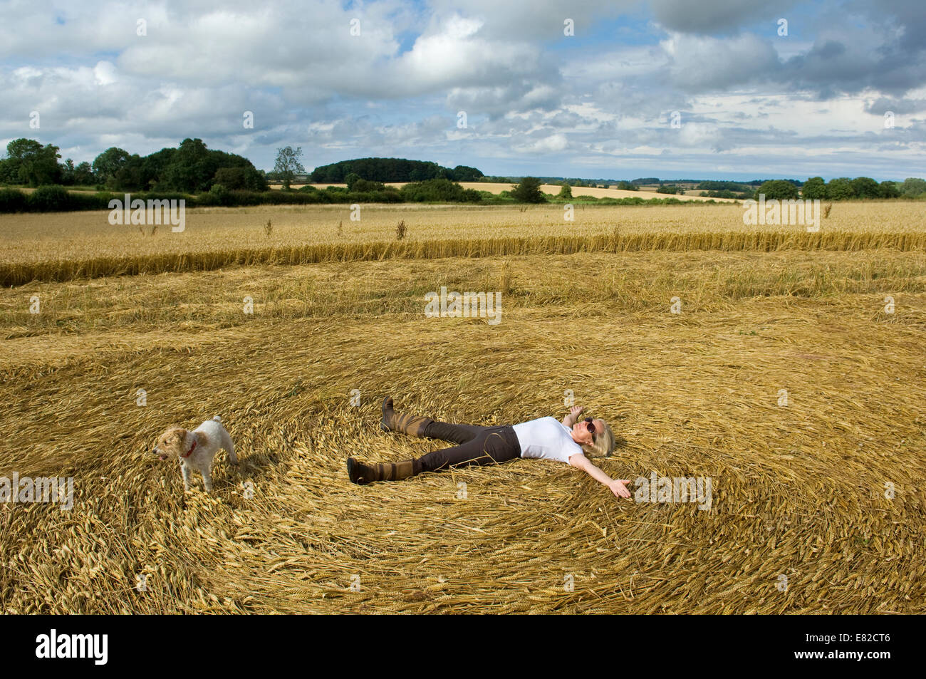 Un agricoltore sdraiato sulla schiena in stoppia di un taglio fresco campo di coltivazione la creazione di un pattern in paglia. Foto Stock