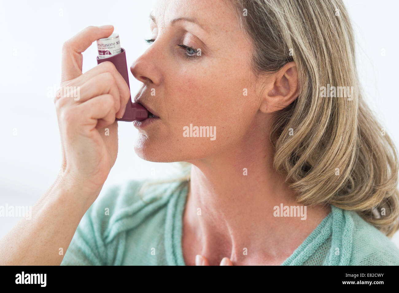 Donna che utilizza un inalatore per aerosol che contiene broncodilatatore per il trattamento di asma, l'inalatore si dilata polmoni airways a im Foto Stock