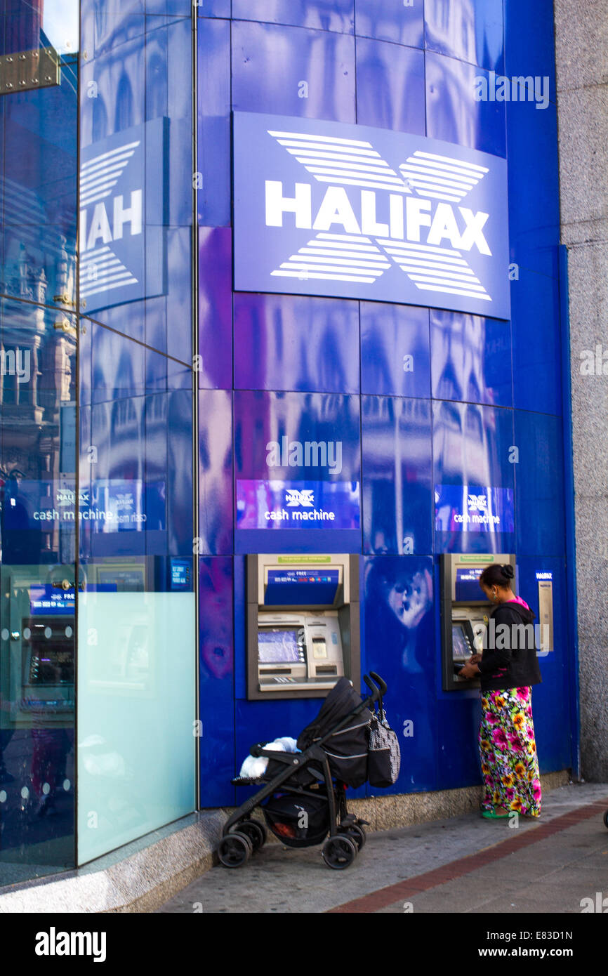 Una donna con un bambino in una sedia push usando un Halifax bancomat in Sheffield Foto Stock