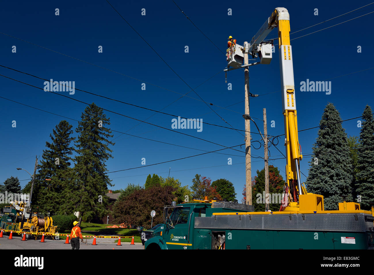 Idro lavoratori stringing overhead di nuove linee elettriche in Toronto con cielo blu chiaro Foto Stock