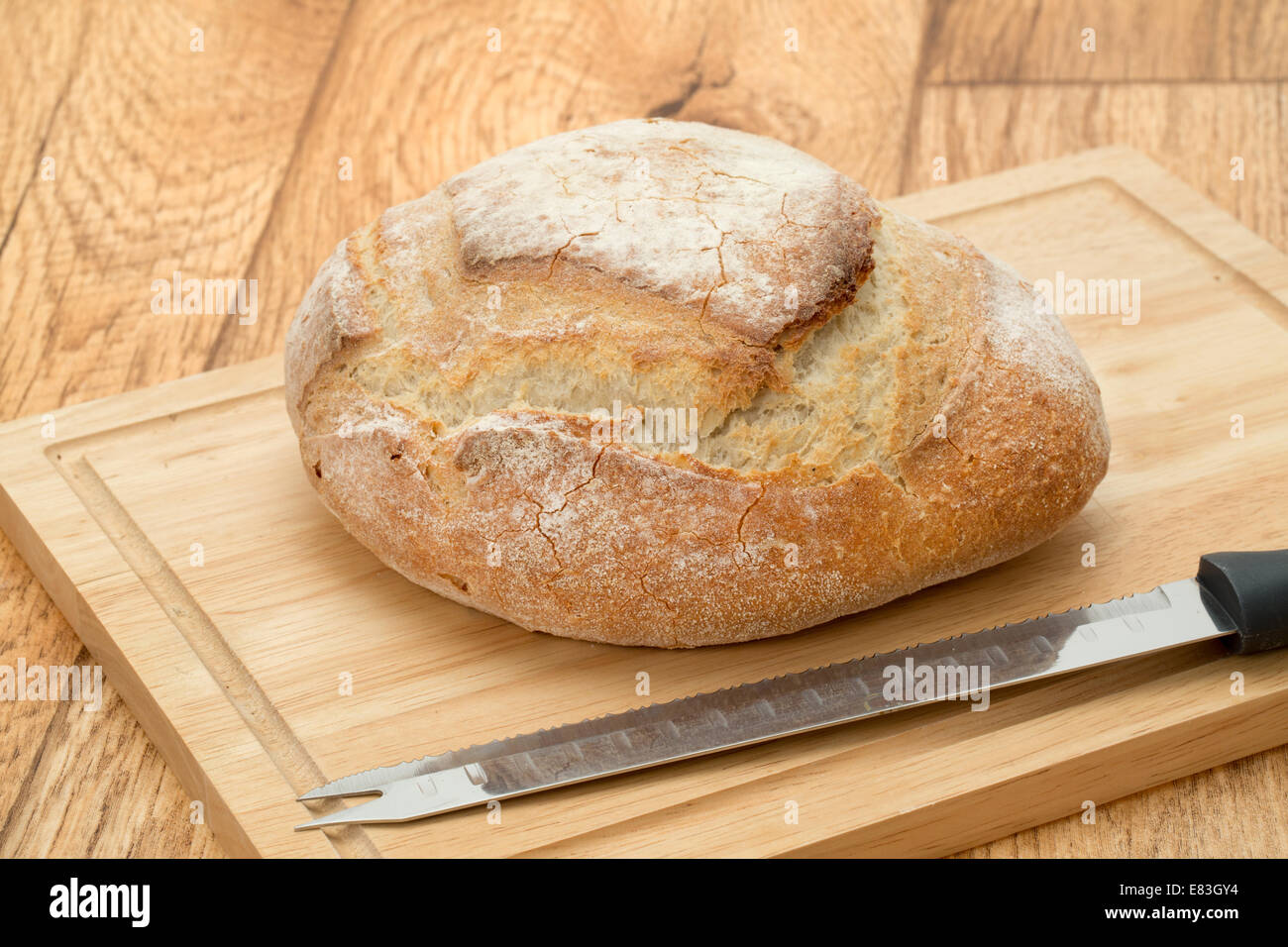 Un rustico francese pagnotta di pane su un tagliere di legno con un coltello per pane - studio shot Foto Stock