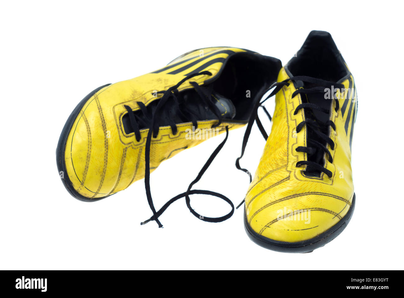 Una coppia di giallo sporco di scarpe da calcio o scarpe da calcio - studio shot con uno sfondo bianco Foto Stock