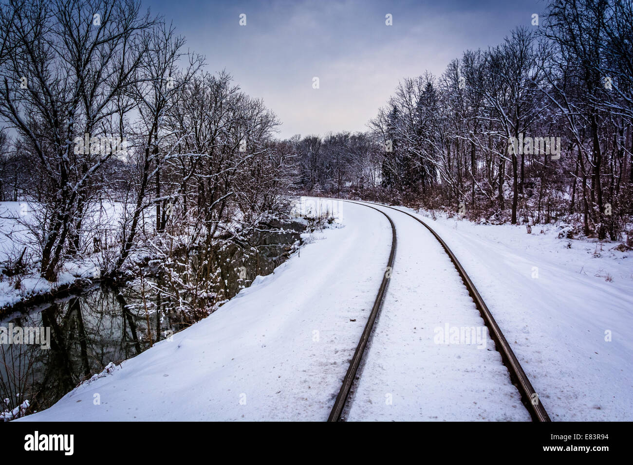 Coperta di neve i binari della ferrovia e creek nelle zone rurali Carroll County, Maryland. Foto Stock