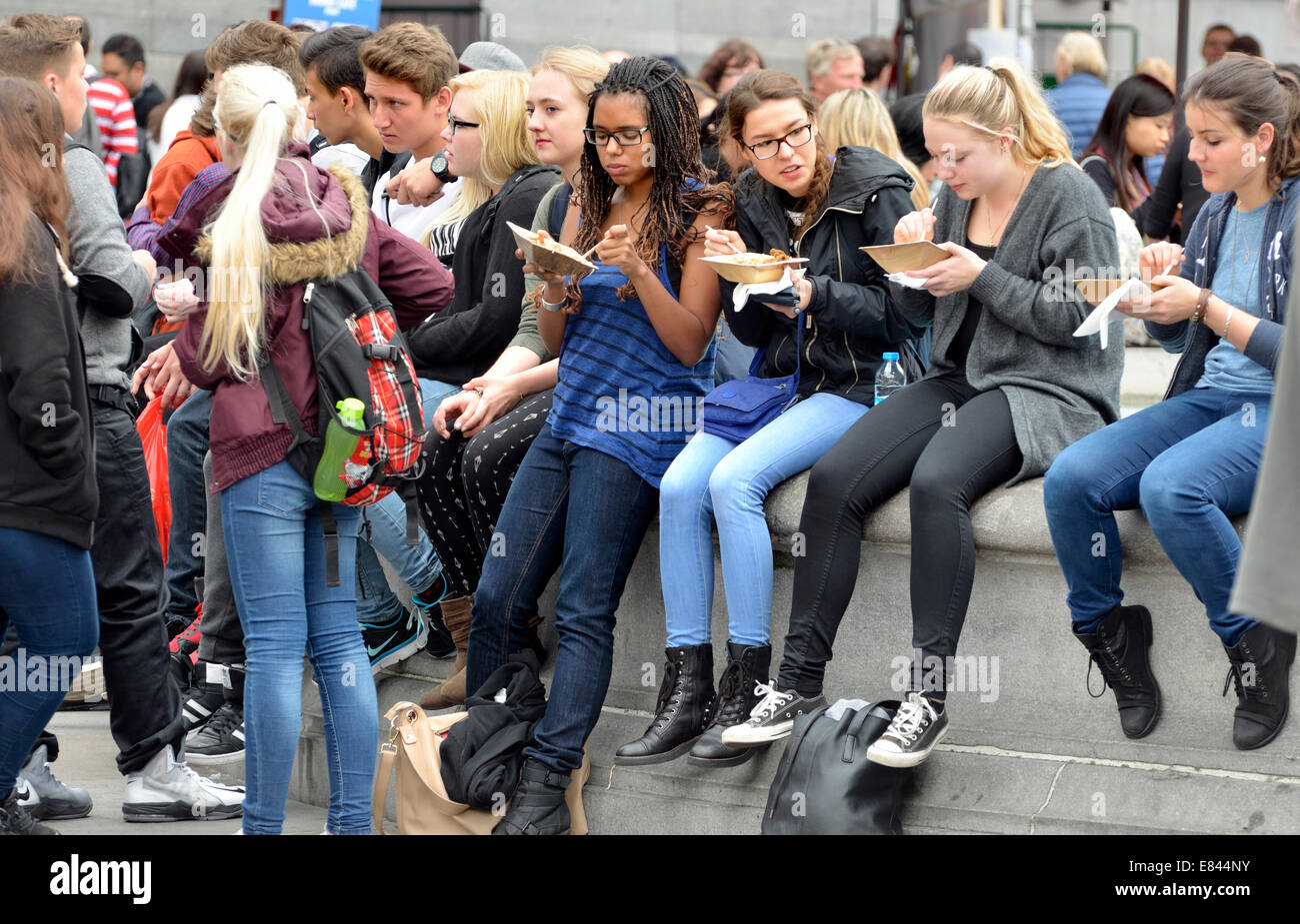 Londra, Inghilterra, Regno Unito. I giovani di mangiare cibo di strada in Trafalgar Square Foto Stock