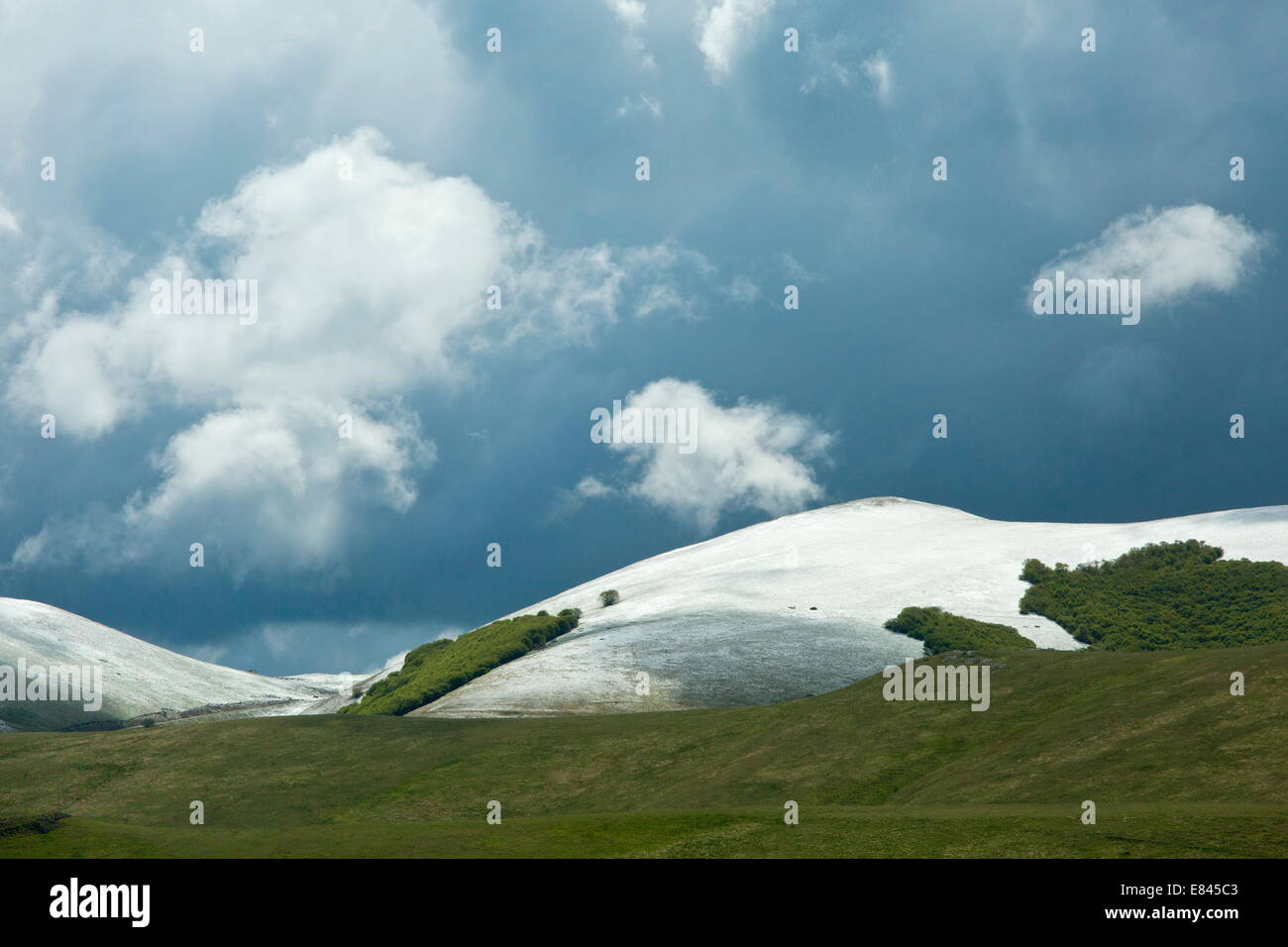 Boschi di faggi, colline, neve e nuvole nel Parco Nazionale dei Monti Sibillini, Italia. Foto Stock