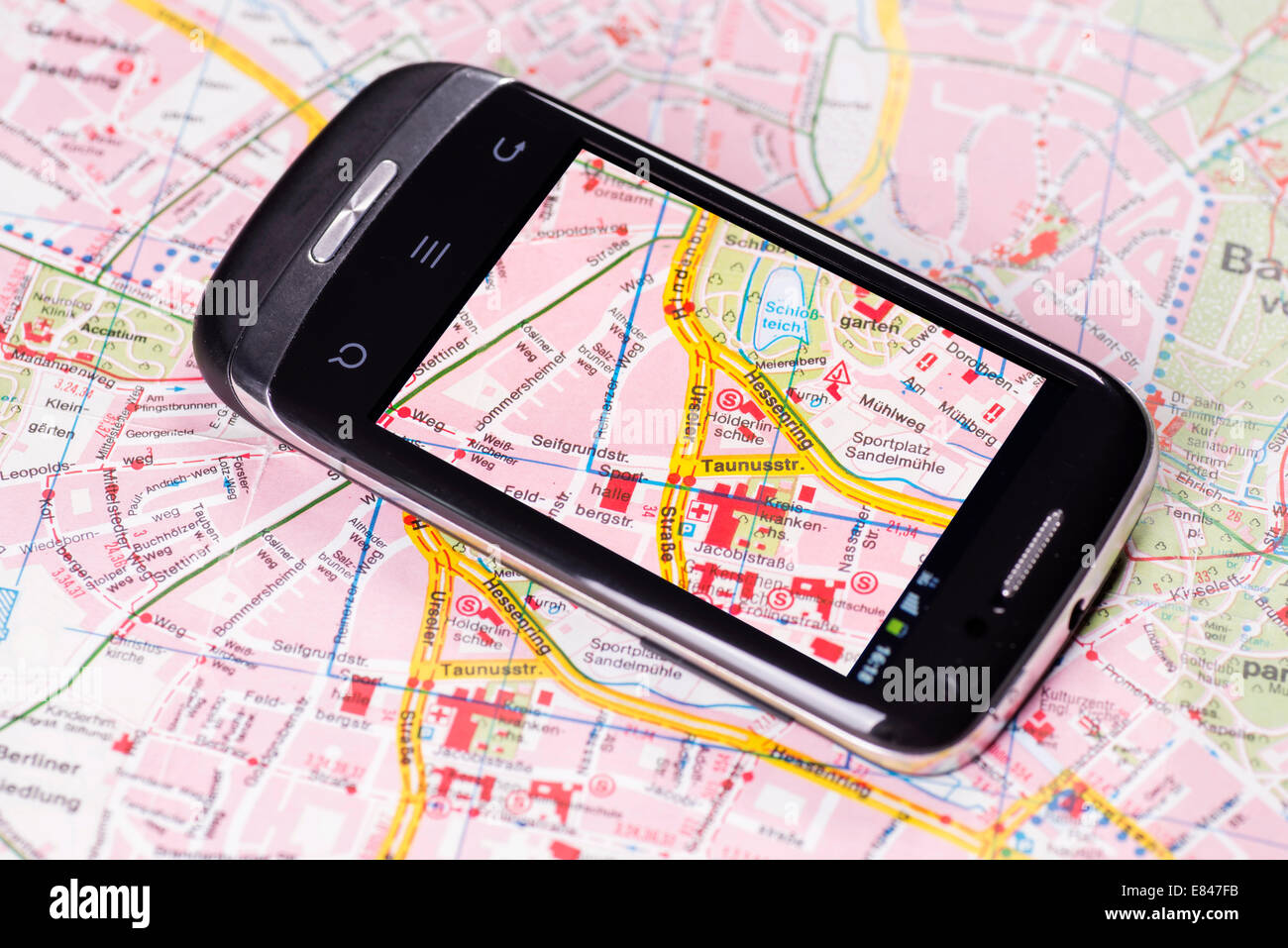 Smart phone con vista mappa si trova su una mappa da stampare. Foto Stock