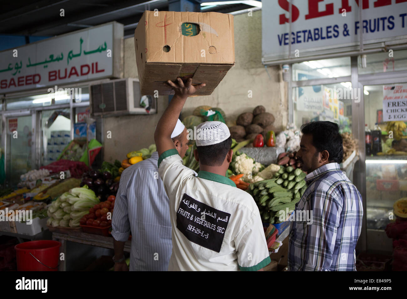 Un lavoratore manuale porta una scatola di produrre attraverso il mercato Deira, Dubai, Emirati Arabi Uniti. Foto Stock