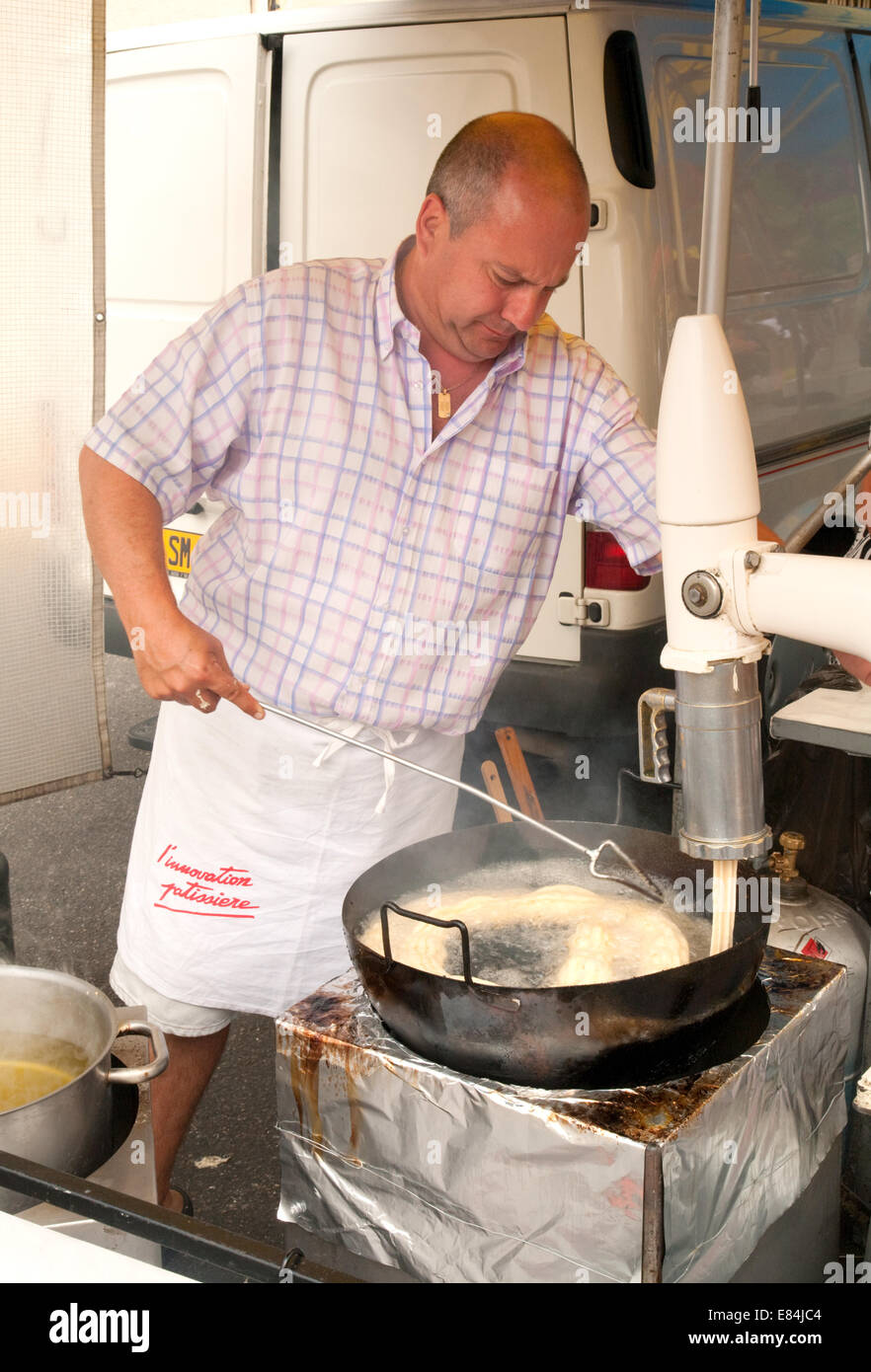 Un baker rendendo le ciambelle (chichi) nel mercato, NERAC, Valle del Lot, Aquitaine, Francia Foto Stock