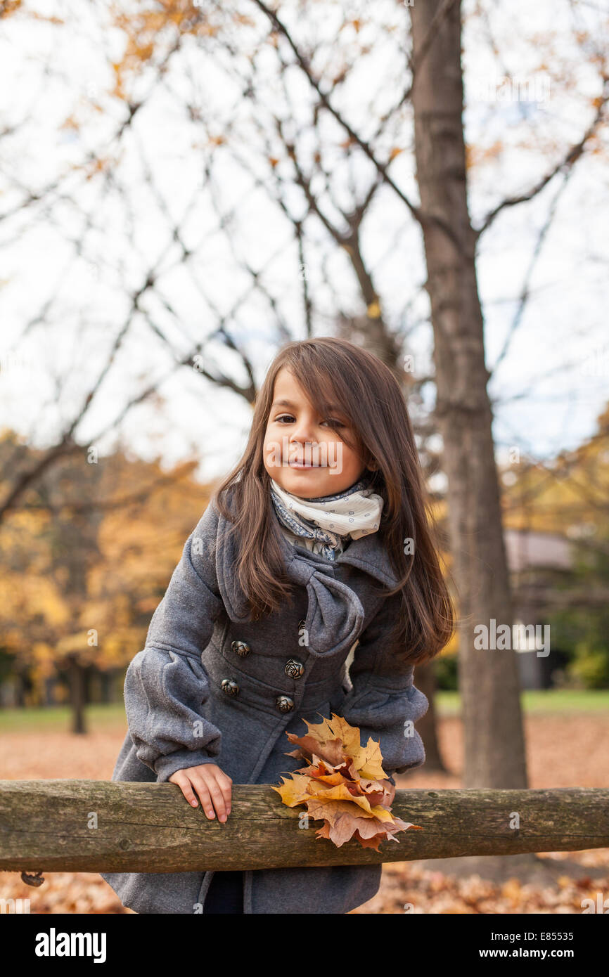 Bambina con le foglie di autunno in un parco di autunno Foto Stock
