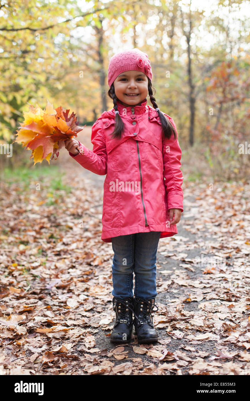Bambina con le foglie di autunno in un parco di autunno Foto Stock