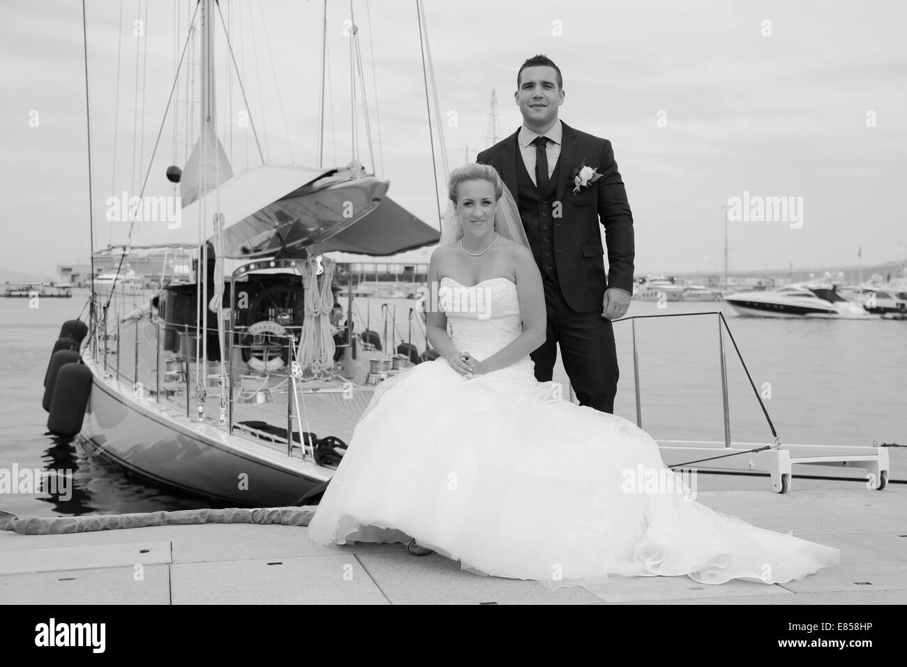 Sposa e lo sposo in posa di fronte a uno yacht in un marina Foto Stock