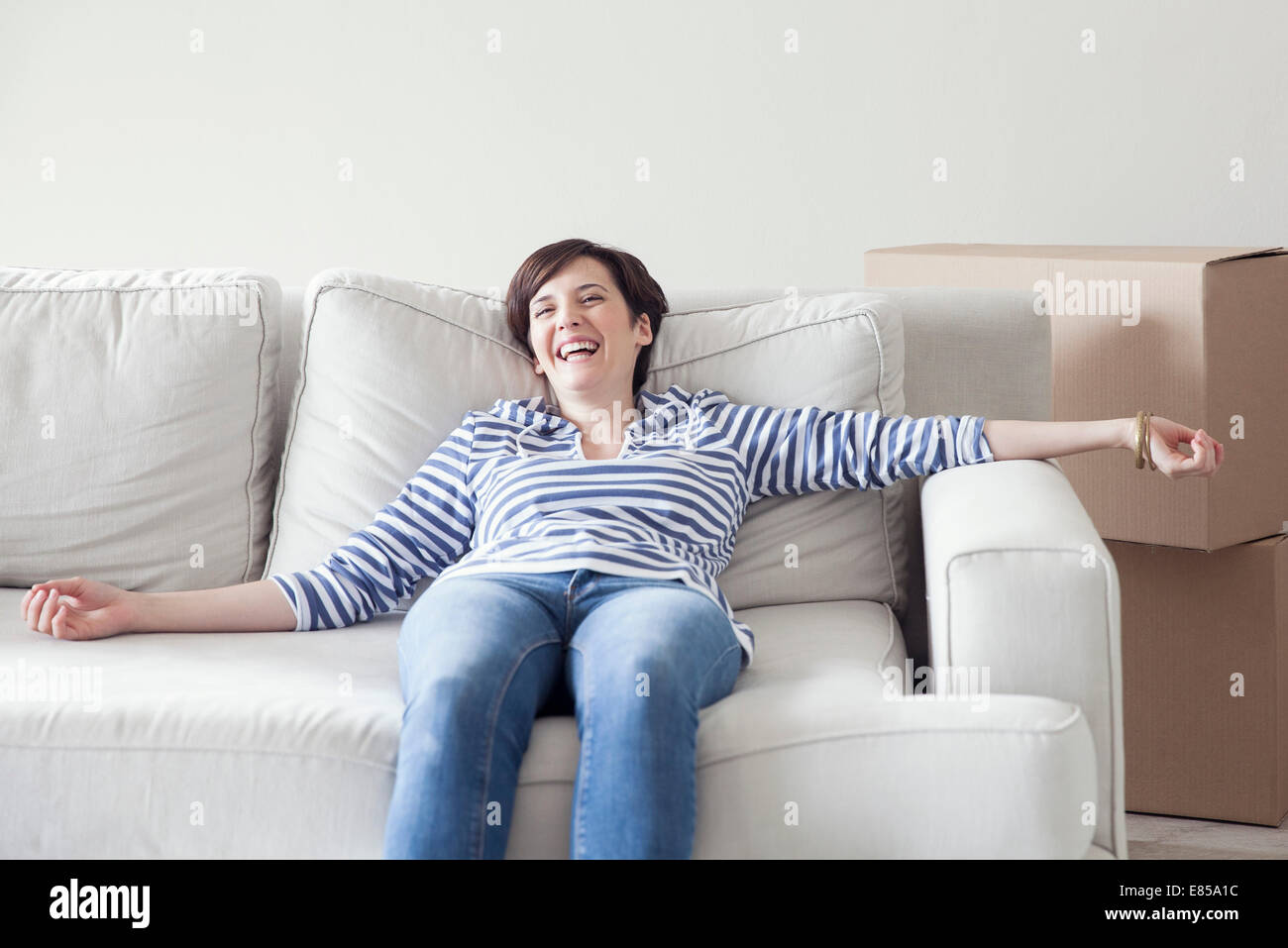 Donna appoggiata sul divano mentre casa in movimento Foto Stock