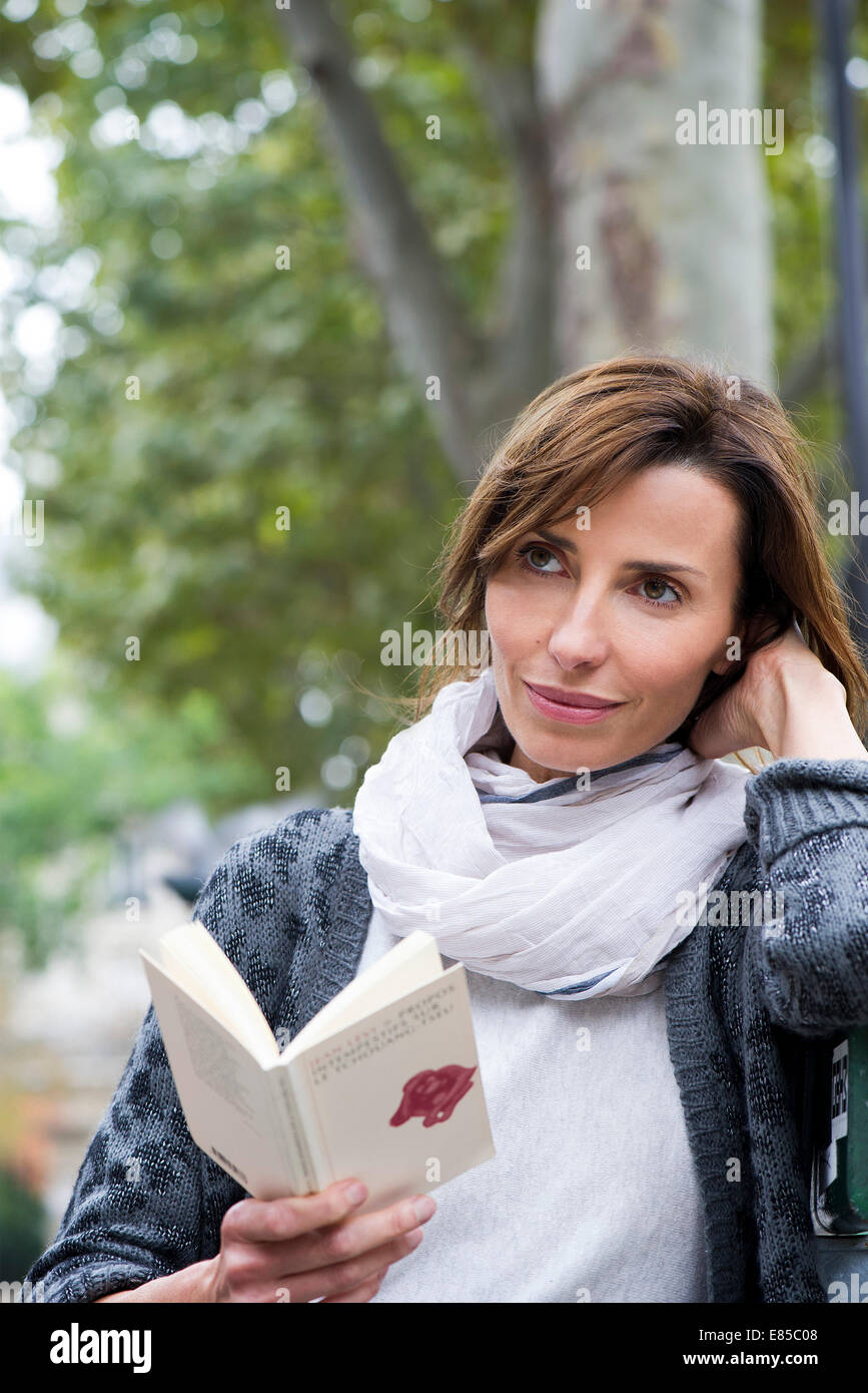 La donna la lettura di libro in brossura in esterno Foto Stock