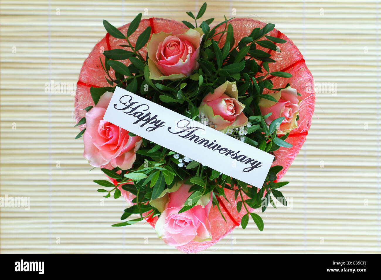 Felice anniversario con la carta a forma di cuore rosa bouquet di rose Foto Stock