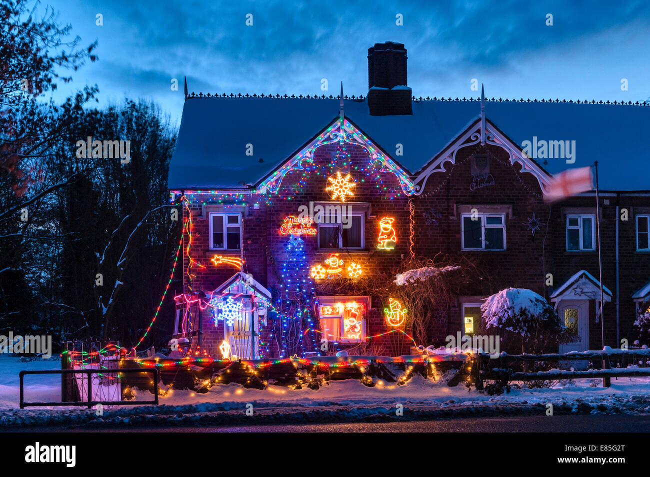 Luci e decorazioni natalizie in un cottage di campagna solitario in una fredda e nevosa serata invernale, Regno Unito Foto Stock