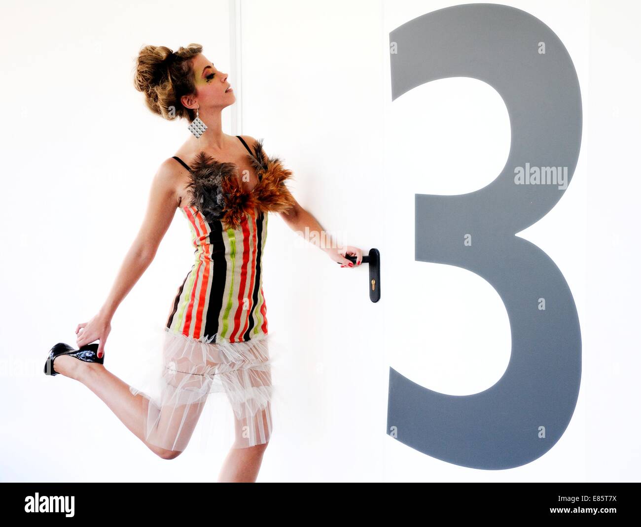 Una donna di apertura di una porta con un gigantesco numero 3 su di esso Foto Stock