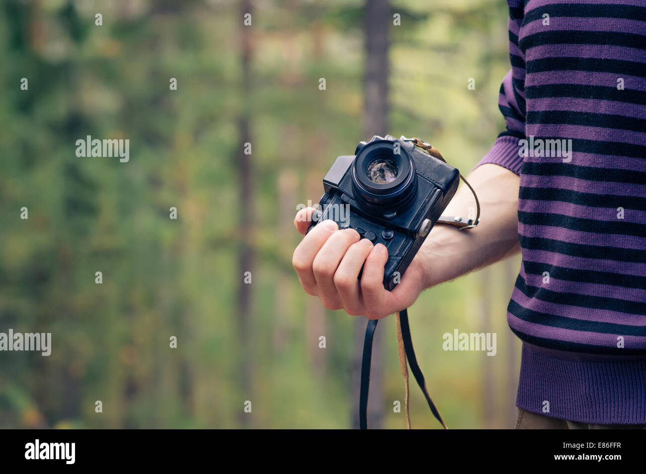 Man mano che tiene retrò fotocamera foto tanga Outdoor Lifestyle con foresta natura sullo sfondo Foto Stock
