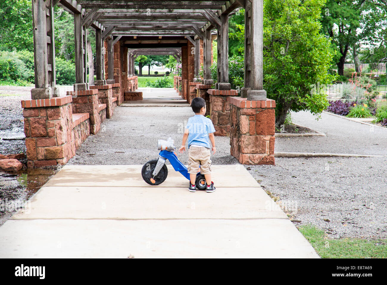 Un giovane ragazzo ispanico gioca con il suo triciclo giocattolo in sarà Roger's Park nella città di Oklahoma, Oklahoma, Stati Uniti d'America. Foto Stock