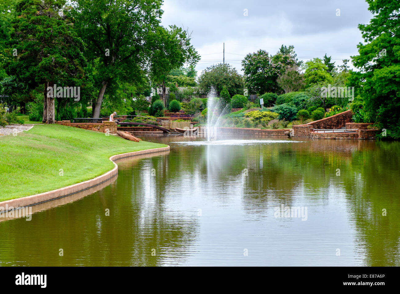 Una vista dello stagno in Will Rogers park nella città di Oklahoma, Oklahoma, Stati Uniti d'America con un giovane uomo godendo della bellezza in background. Foto Stock