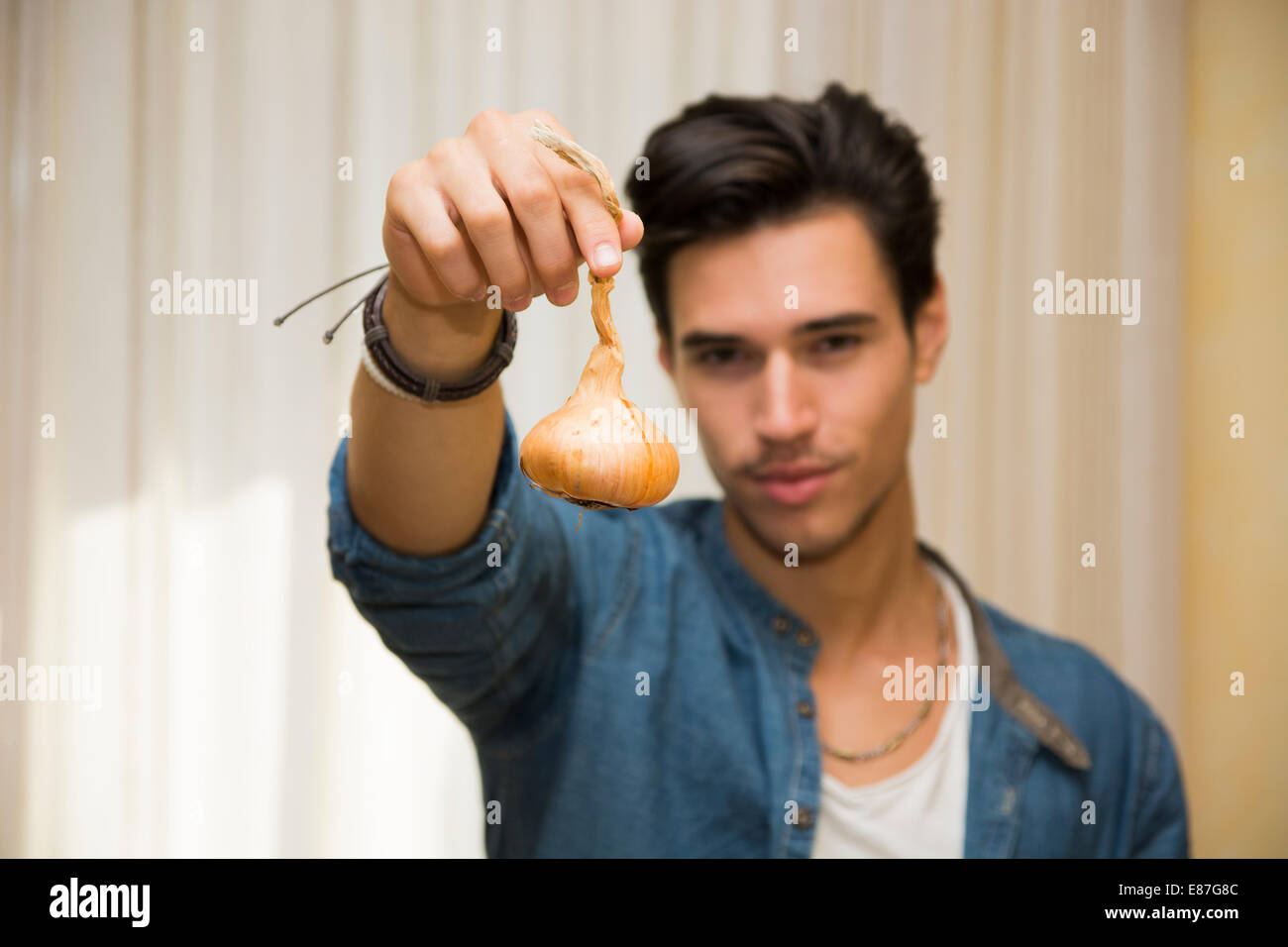 Sorridente giovane azienda una cipolla fresca nella sua mano in una dieta sana e uno stile di vita vegetariano o concetto Foto Stock