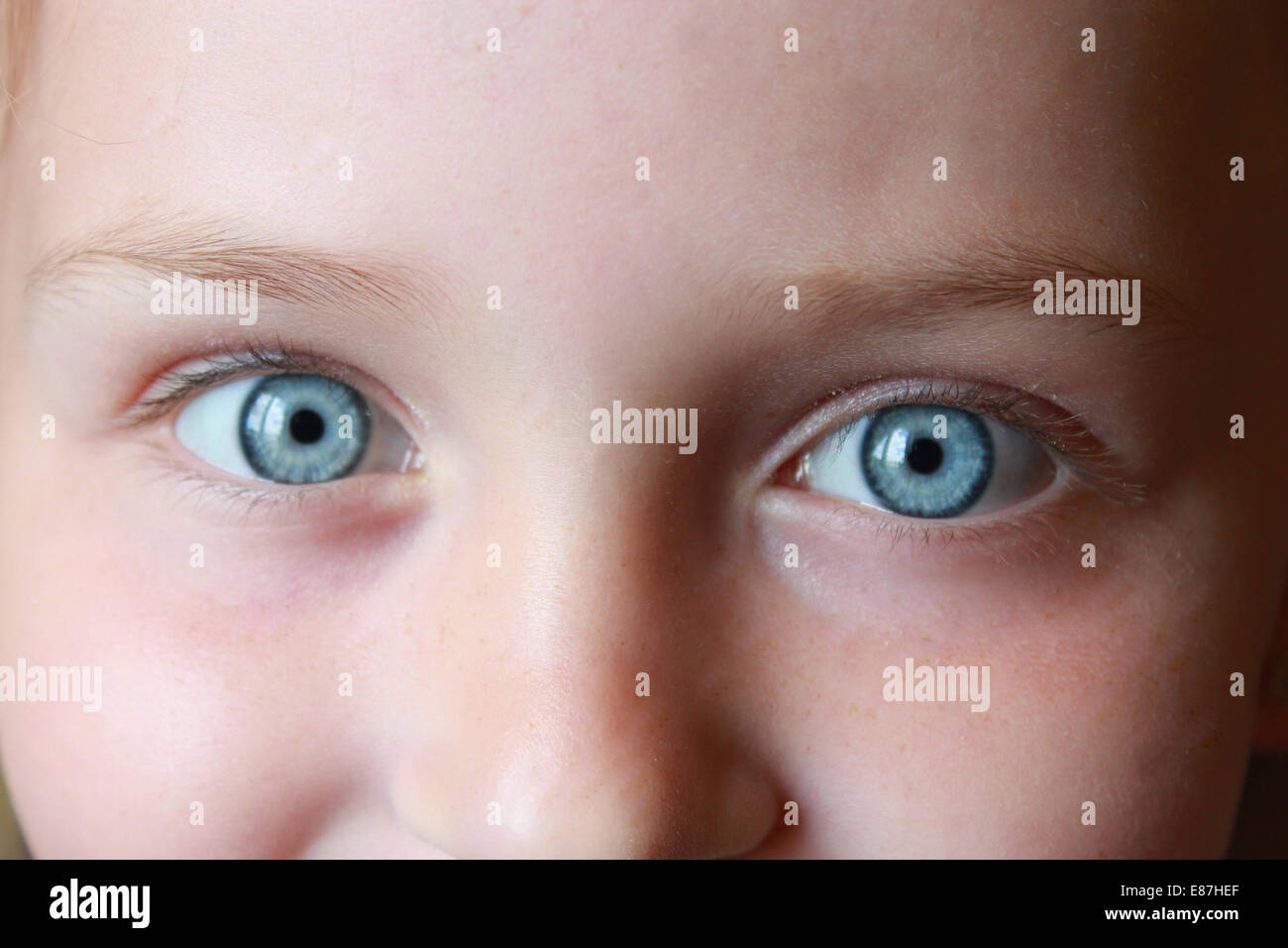 Gioia bambina's blue eyes staring fino e sorridente Foto Stock