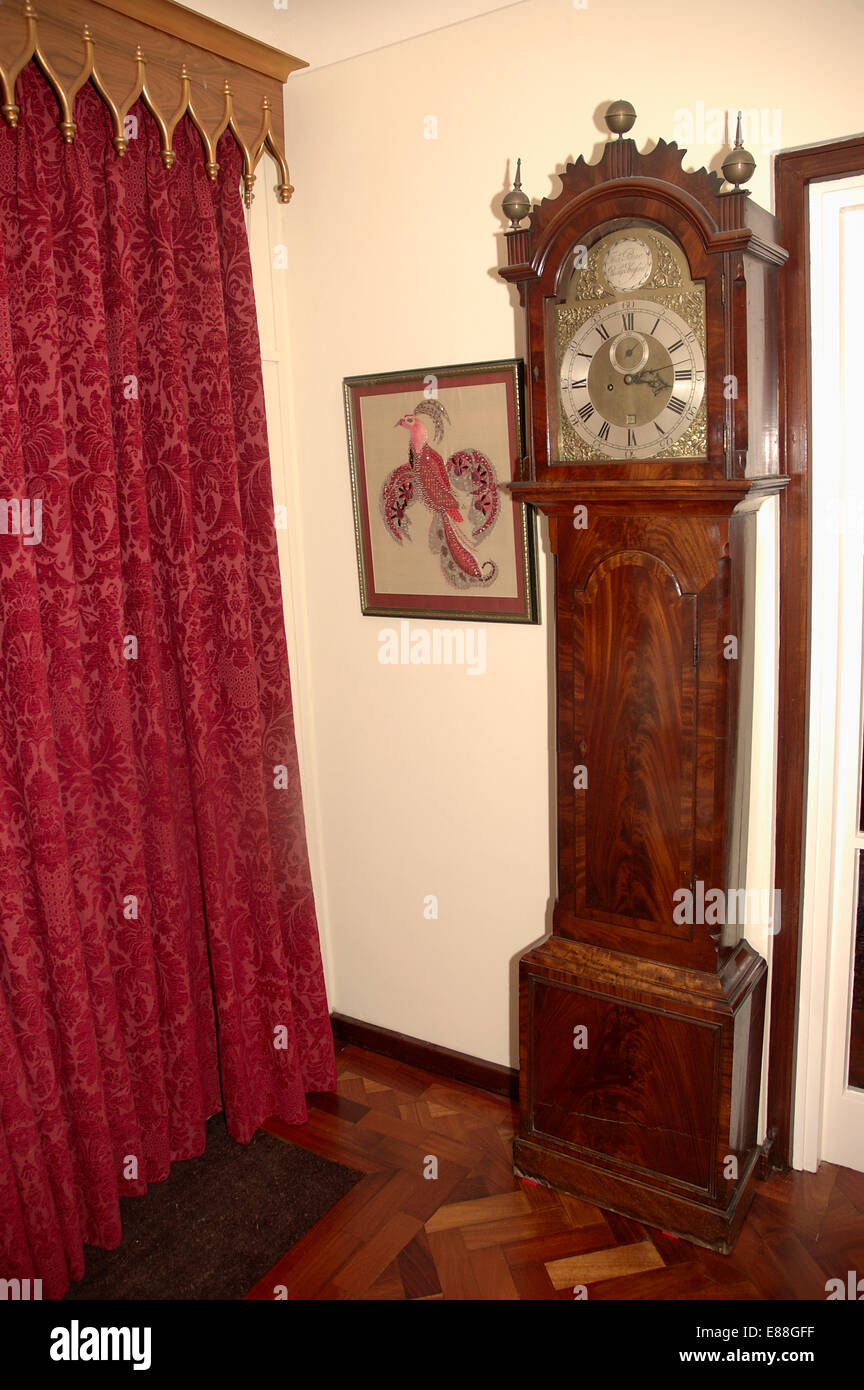Antico orologio longcase accanto tende rosse con in legno dorato mantovane Foto Stock