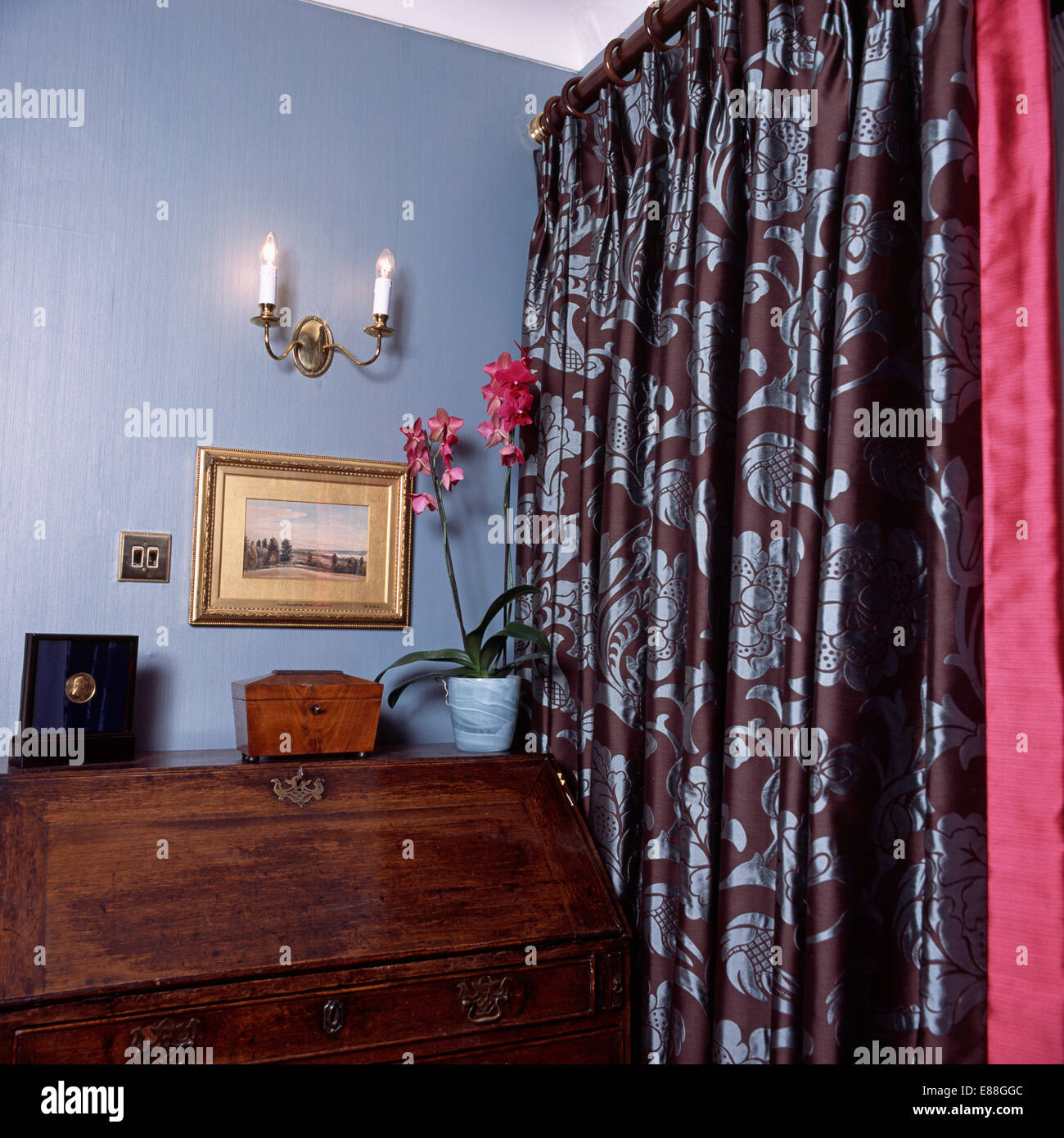 Antica scrivania e blu e marrone tende a motivi geometrici in angolo di blu stanza vivente Foto Stock