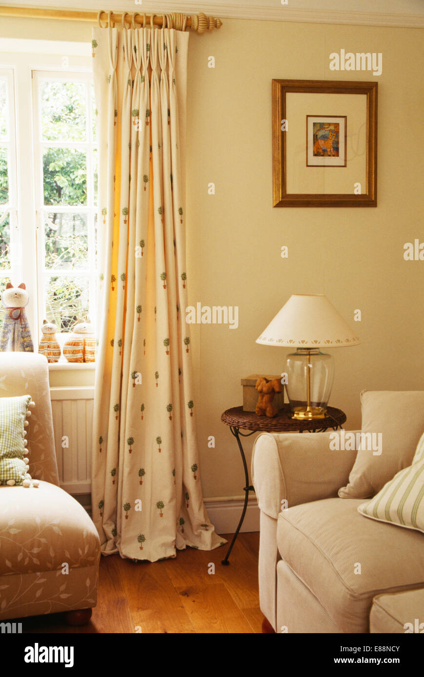 Topiaria da-crema modellato tende su palo di legno sulla finestra in crema paese soggiorno con divani color crema Foto Stock