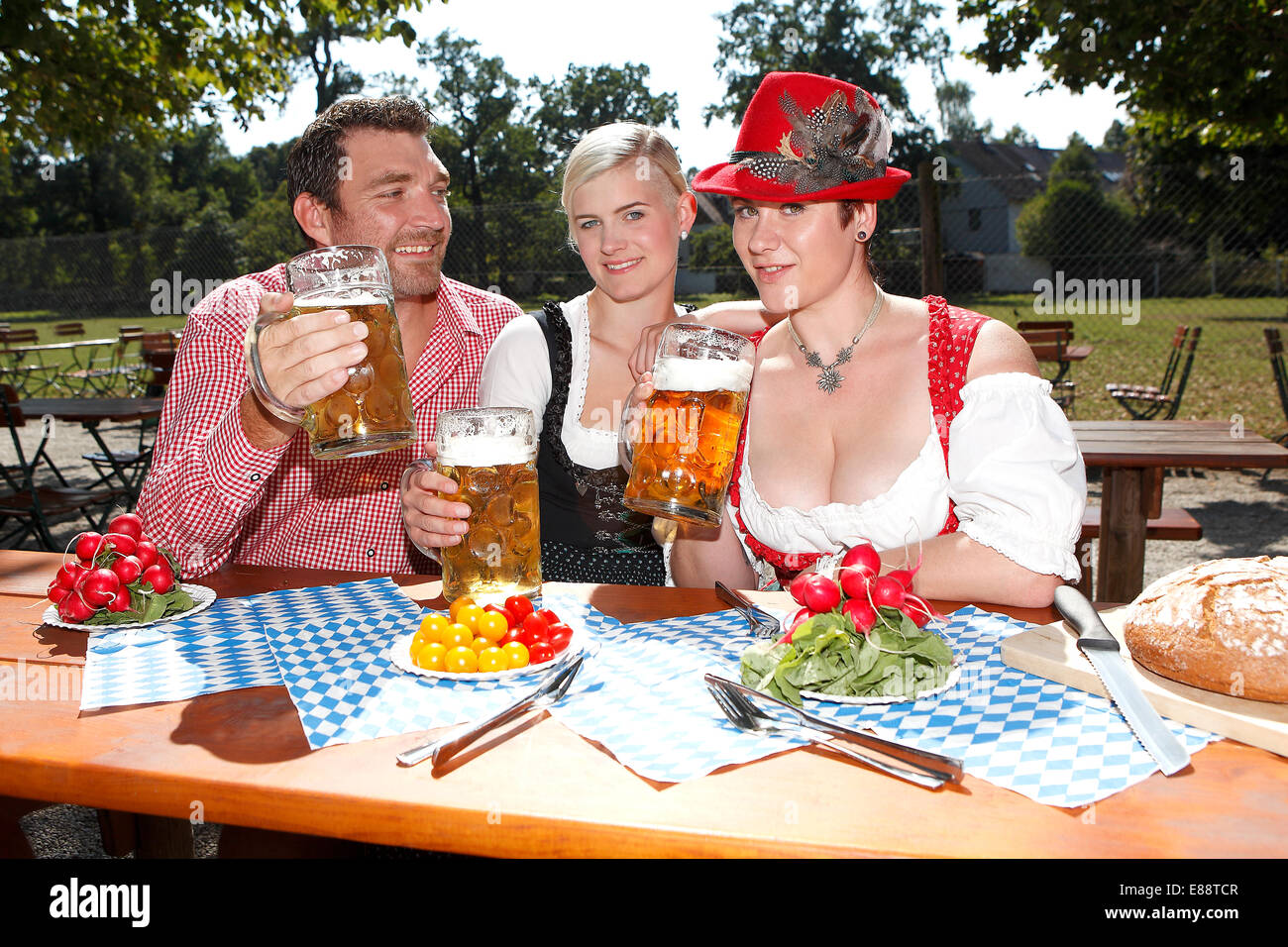 Tre bavaresi seduti in un giardino della birra in Baviera Foto Stock