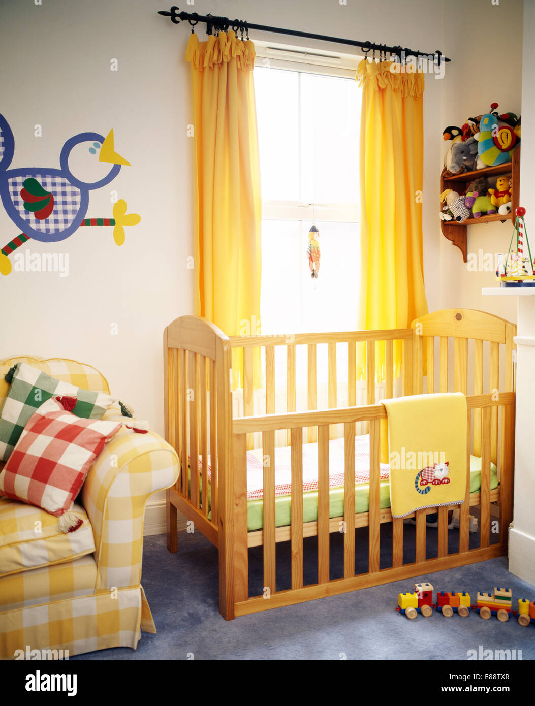 Bambino lettino in legno nella parte anteriore del vetro con tende gialle nella camera da letto di vivaio Foto Stock