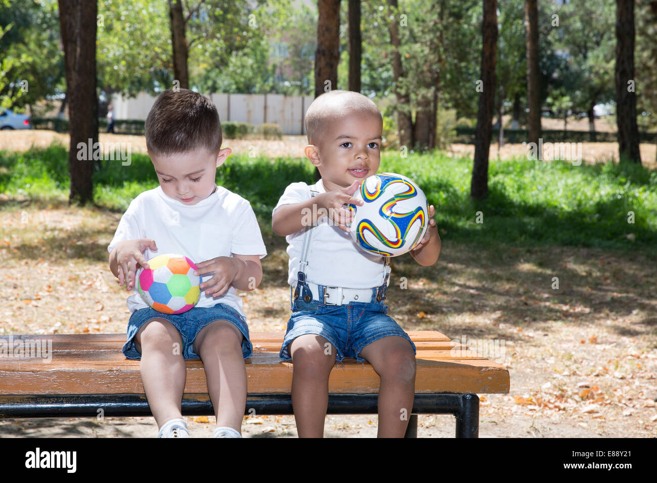 Ragazzi piccoli: americano africano e caucasico con pallone da calcio nel parco sulla natura in estate. Utilizzarlo per bambino e sport concept Foto Stock