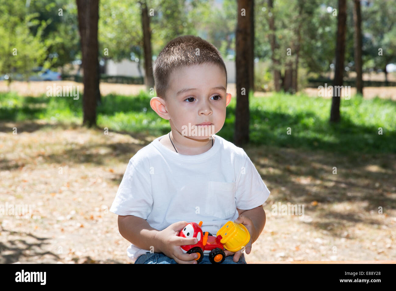 Grazioso fanciullo ragazzo gioca con il giocattolo auto nel parco sulla natura in estate. Utilizzarlo per bambino, genitorialità o il concetto di amore Foto Stock