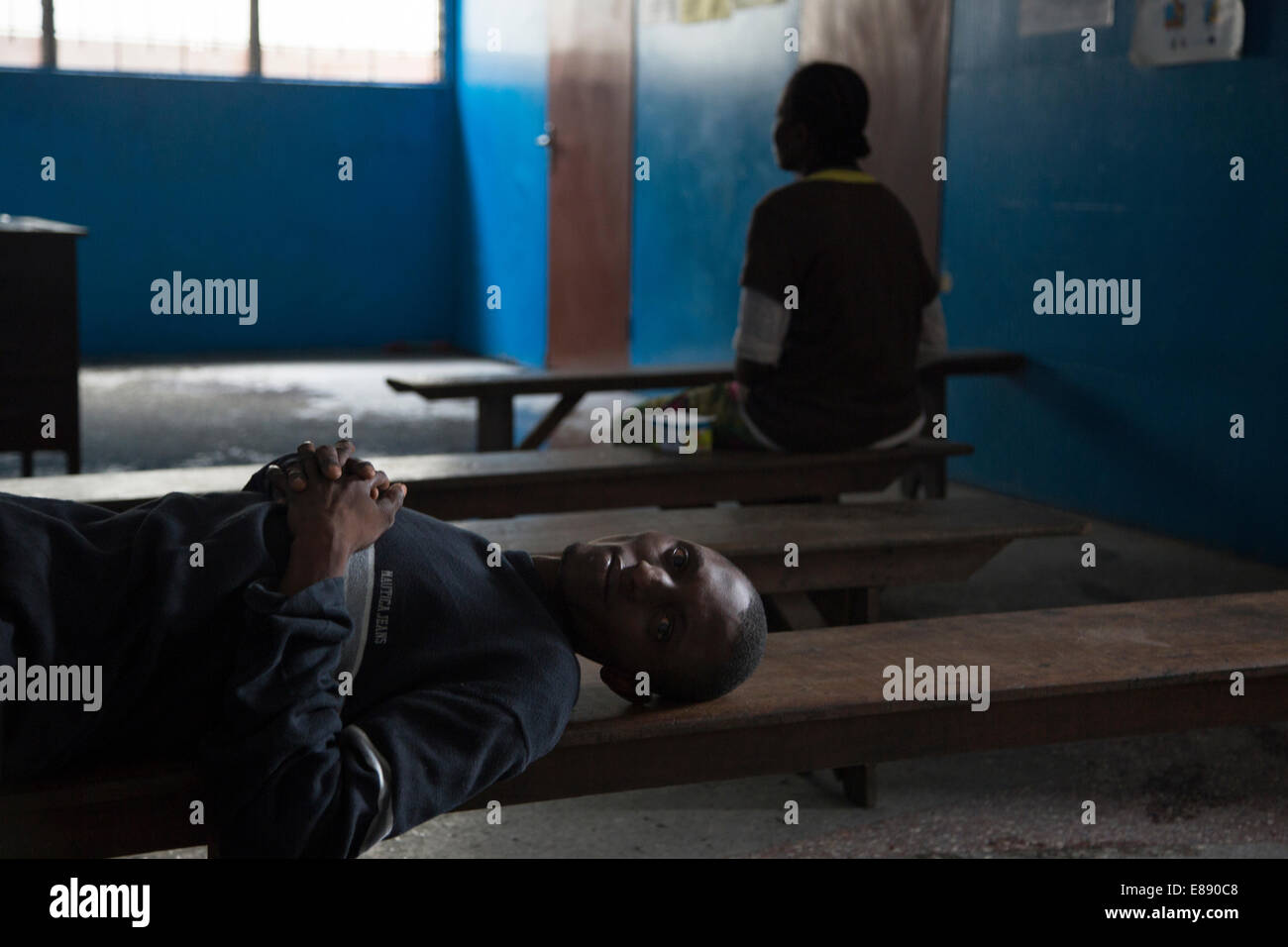 Un uomo sospettato di essere malati con il virus di Ebola attende presso una struttura sanitaria essendo frequentemente visitato da pazienti regolari. West Point Foto Stock