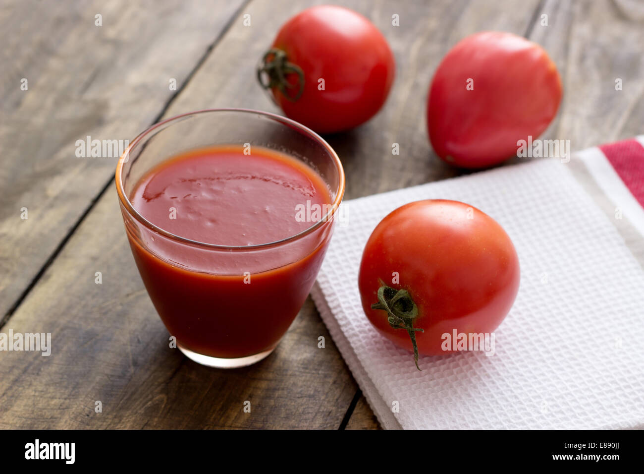 Il succo di pomodoro in vetro e pomodori freschi su vintage tavolo in legno Foto Stock