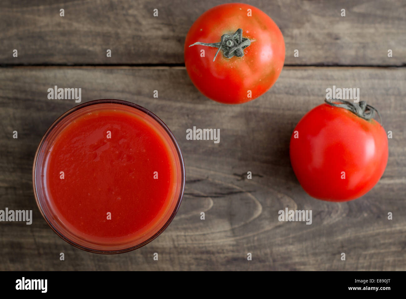 Il succo di pomodoro in vetro e pomodori freschi su vintage tavolo in legno Foto Stock
